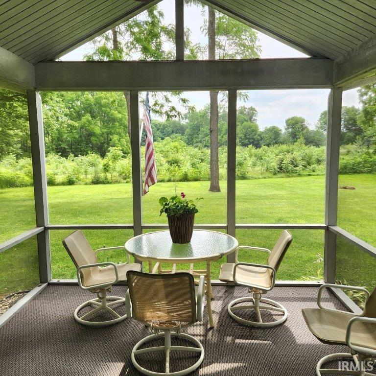 Screened porch featuring a vaulted ceiling and textured flooring
