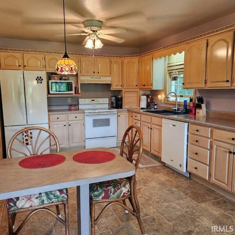 Kitchen featuring light wood cabinetry, white appliances, and a double basin sink