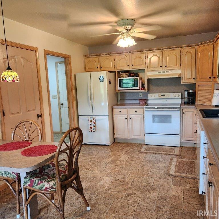 Kitchen featuring extensive cabinetry, laminate flooring, ceiling fan, and built-in appliances