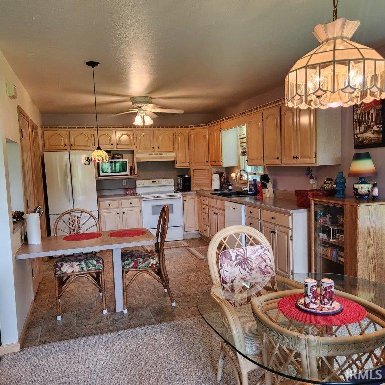 Kitchen featuring light wood cabinetry, white appliances, and a double-basin sink