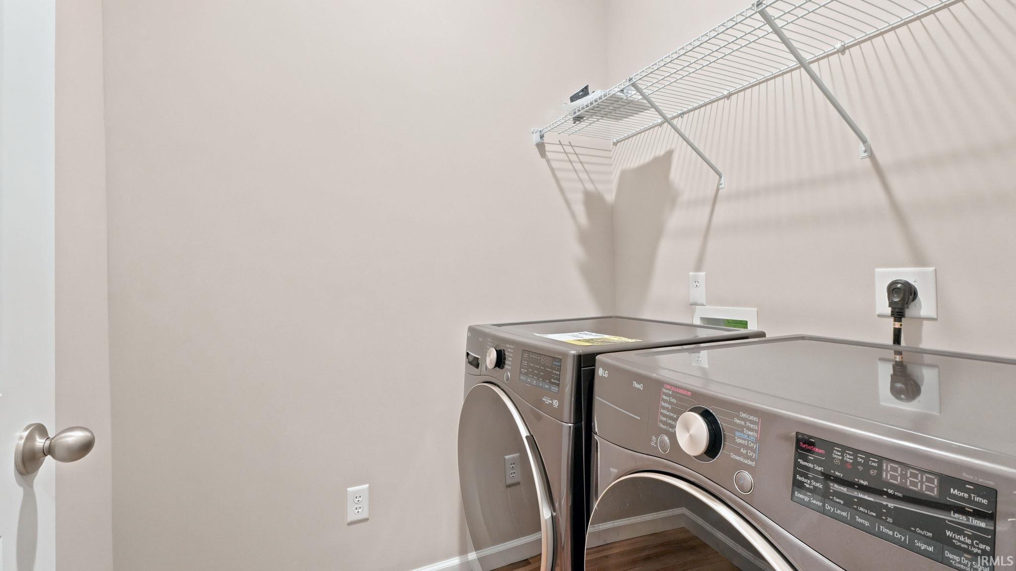 Dedicated laundry area featuring a wire storage shelf, light neutral wall paint, and wood-finish flooring