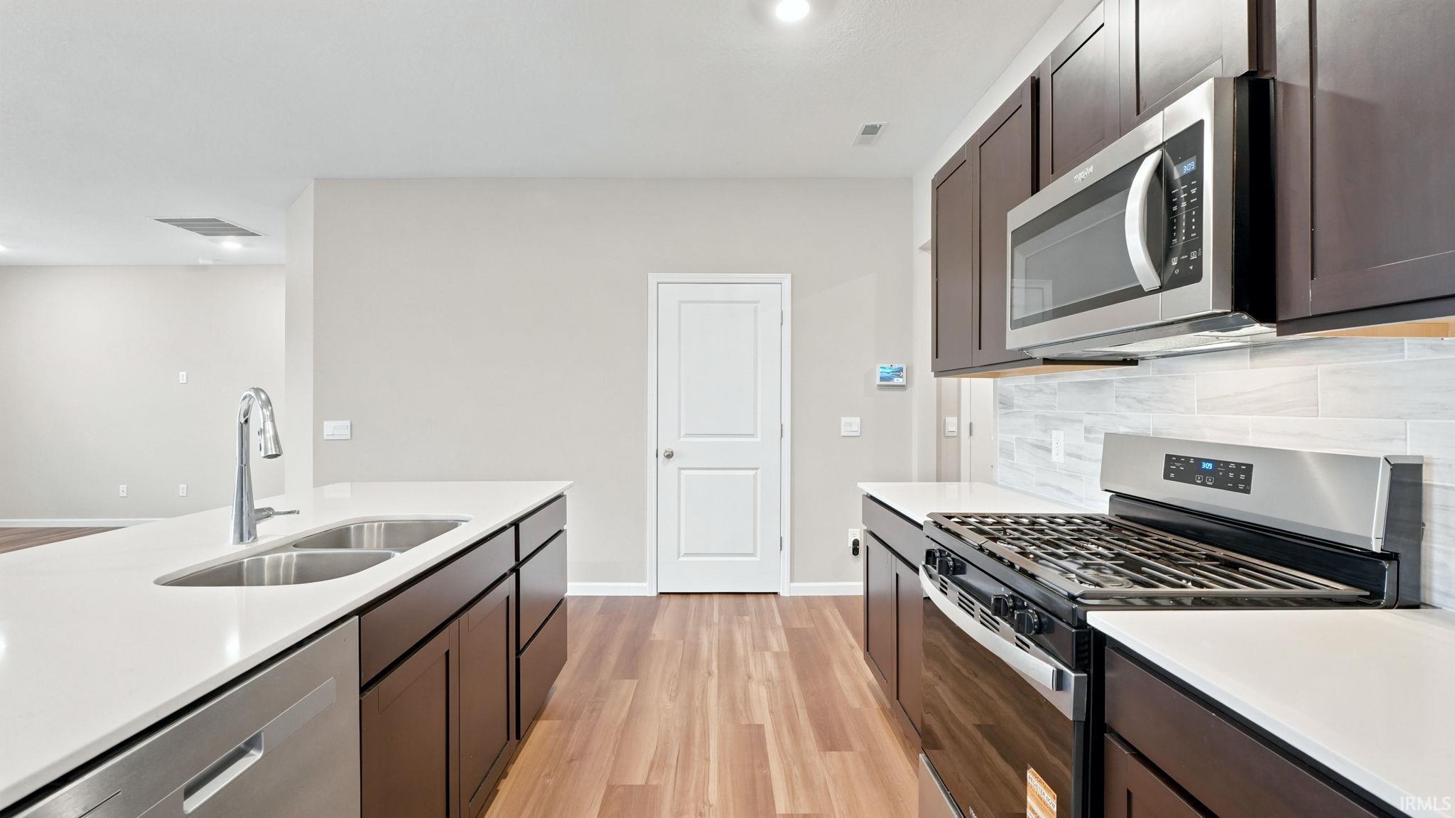 Modern kitchen featuring dark wood-finish cabinetry, light countertops, and wood-finish flooring