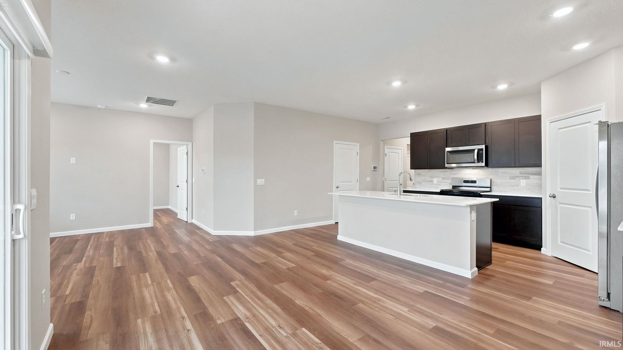 Open-concept living space featuring wood-finish flooring, recessed lighting, and light gray wall tones