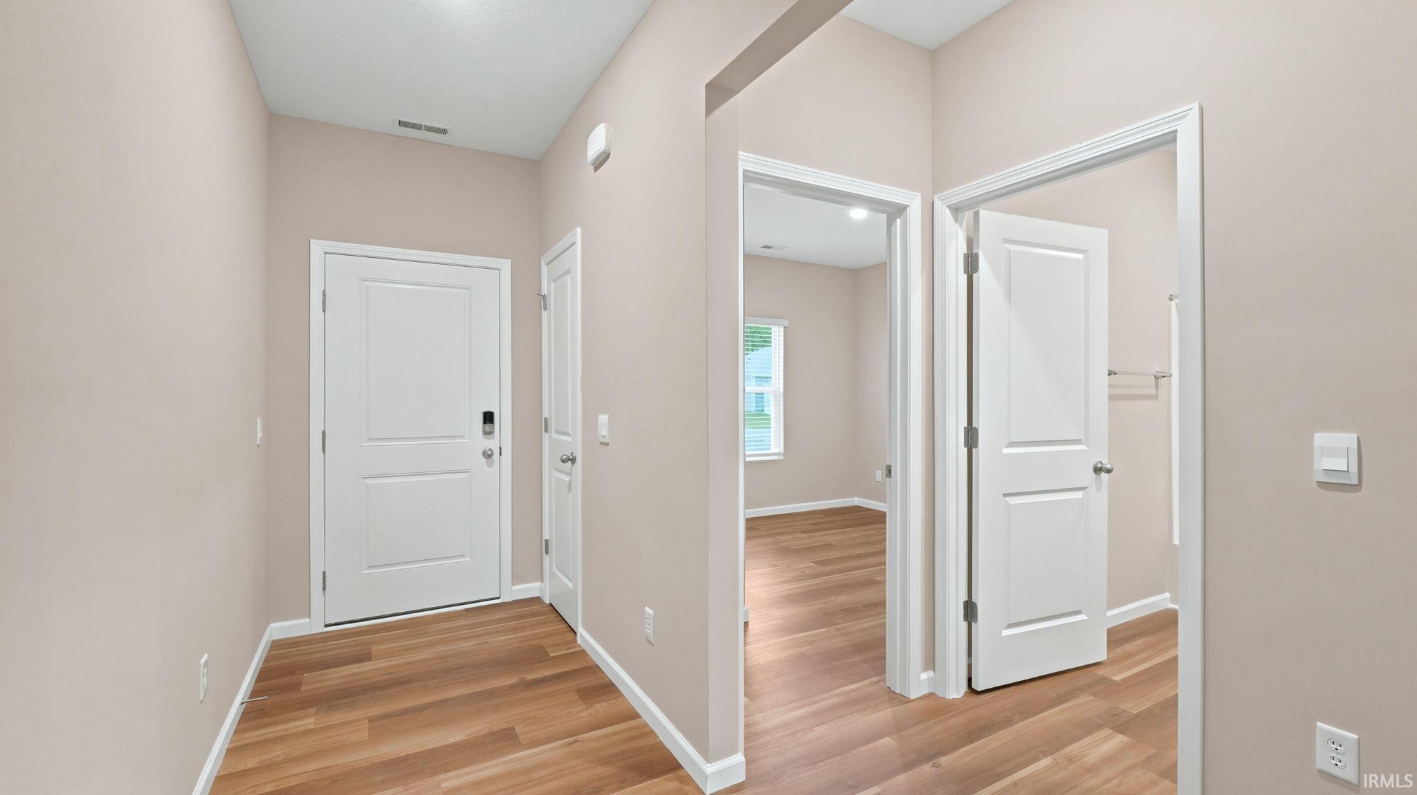 Entryway featuring wood-finish flooring, light neutral wall tones, white trim, and a contemporary door with digital lock