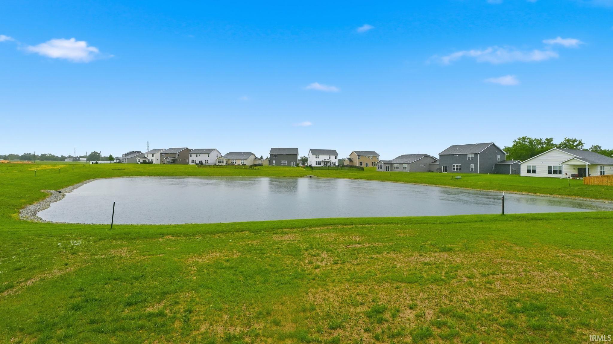 Expansive green space surrounding a tranquil pond, featuring mature landscaping and a serene water element