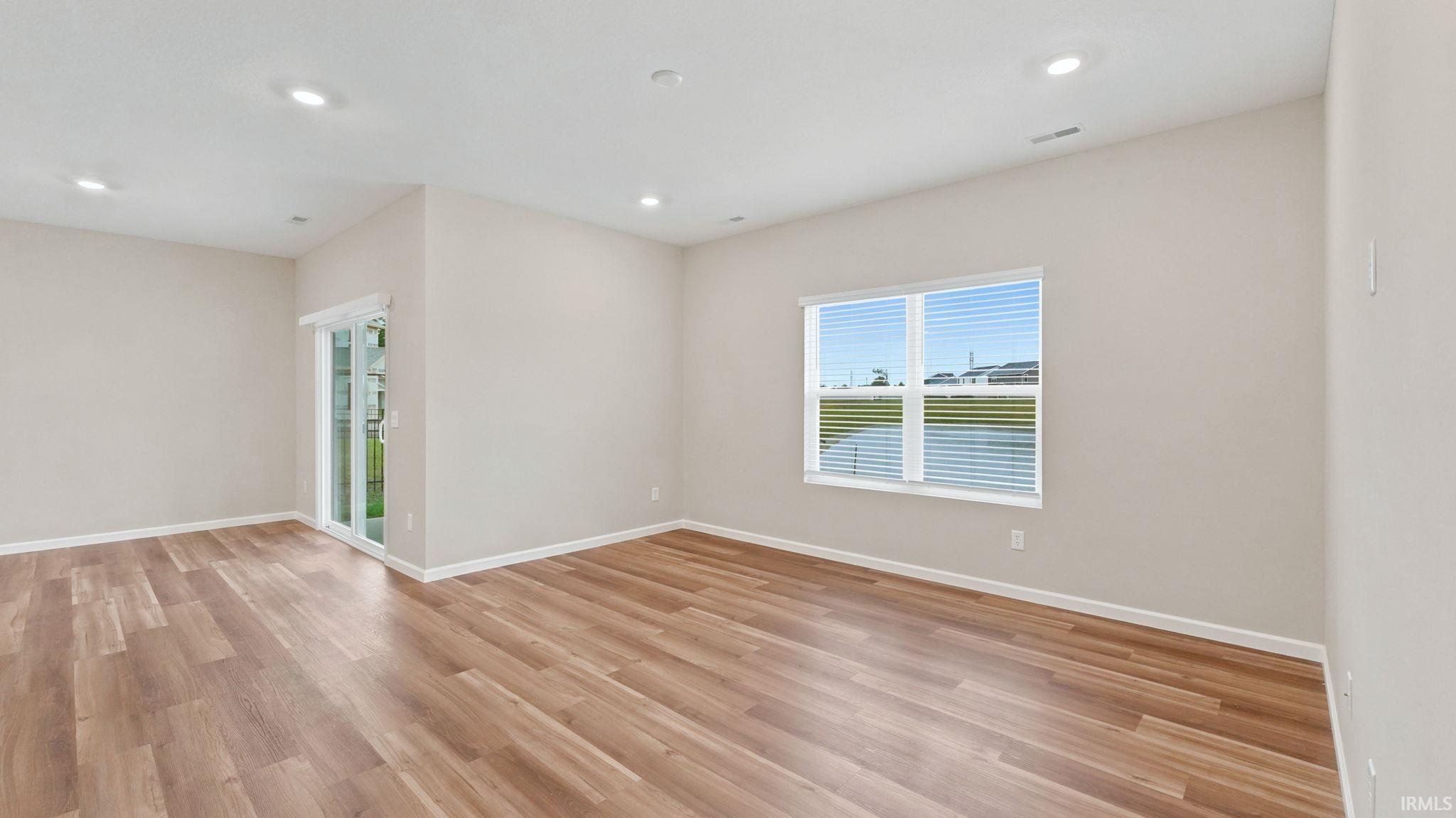 Spacious room featuring wood-finish flooring and neutral wall tones