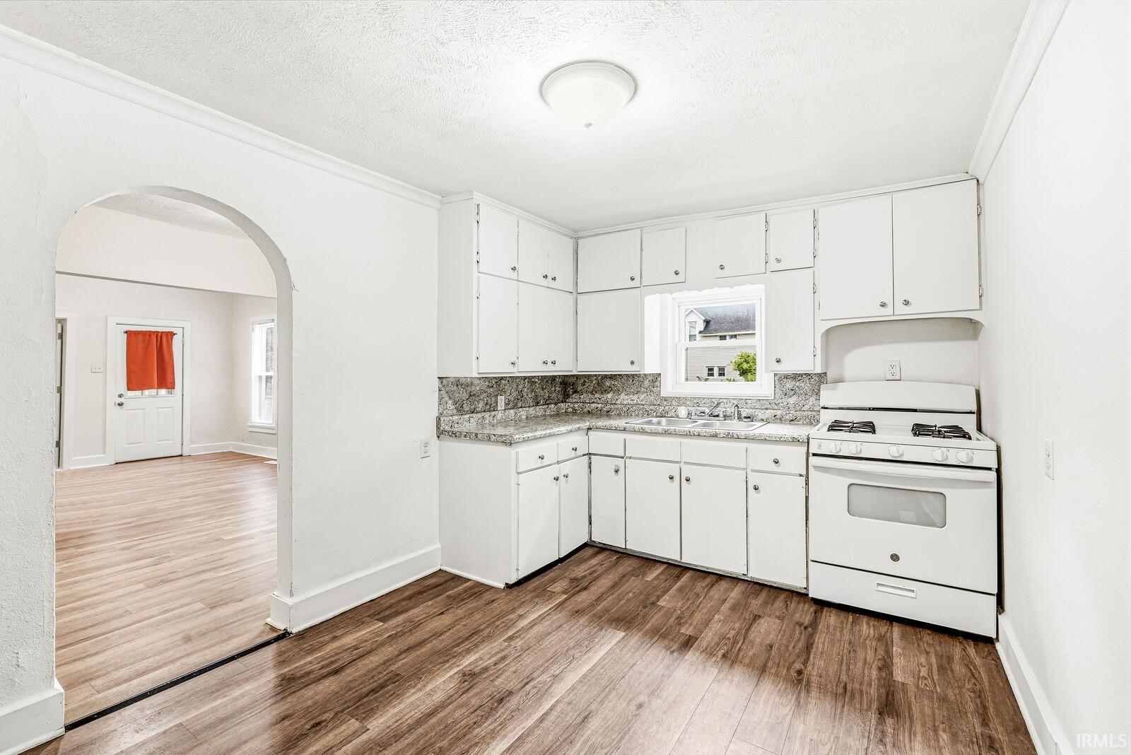 Kitchen featuring white cabinetry, a gas range, a double basin sink, and wood-finish flooring