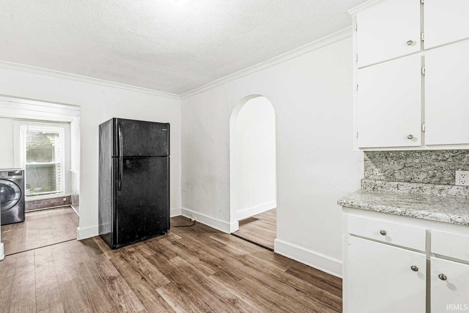 Kitchen area featuring wood-finish flooring, white cabinetry, and a light-colored countertop with a matching backsplash