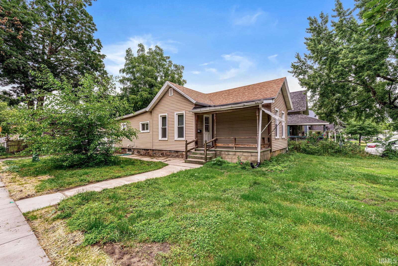 Traditional-style home featuring tan siding and a brown shingle roof