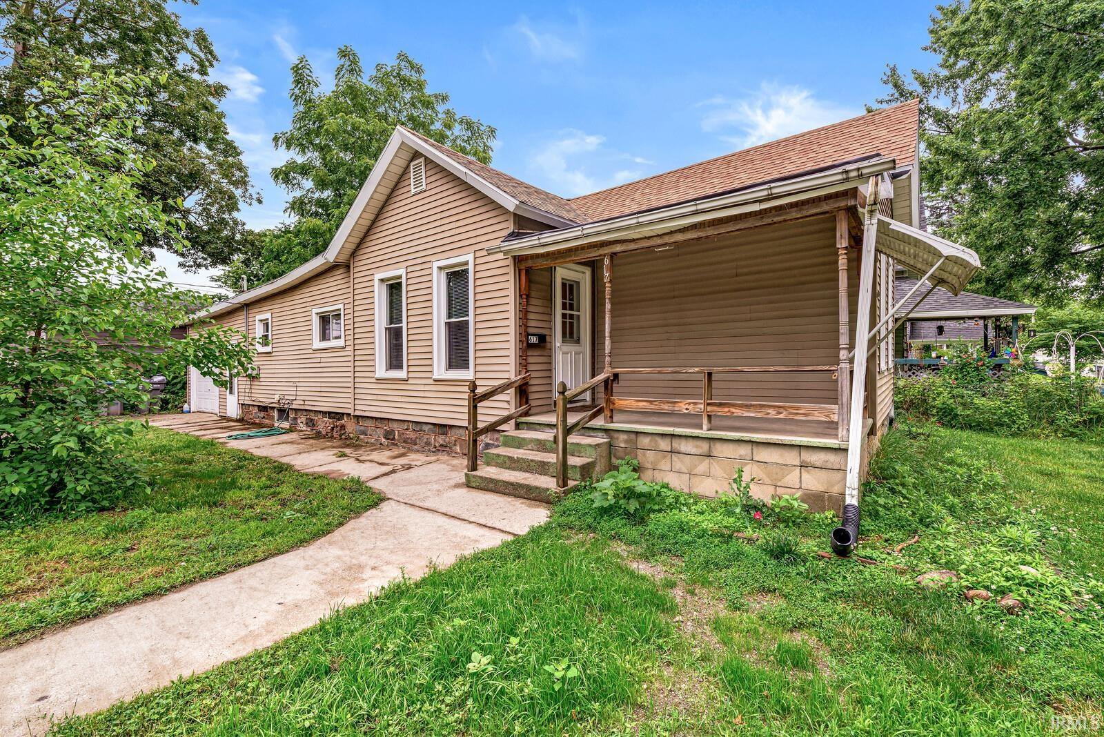 Single-story residence featuring light brown horizontal siding and a covered front porch with steps