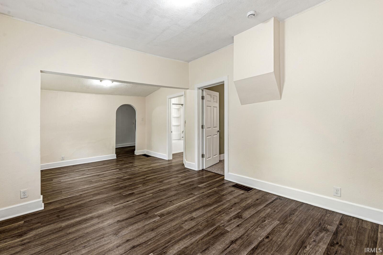 Spacious room featuring wood-finish flooring, white baseboards, and neutral wall tones