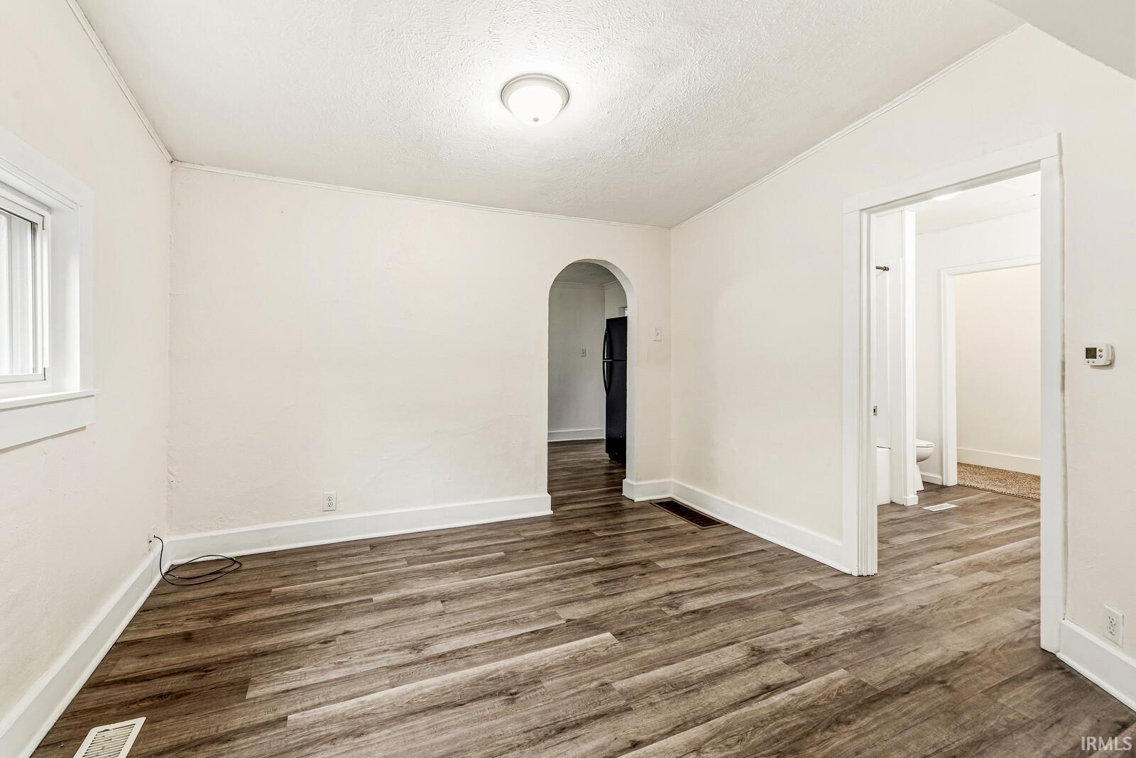 Interior space featuring wood-finish flooring, white baseboards, and a white ceiling with a flush-mount light fixture
