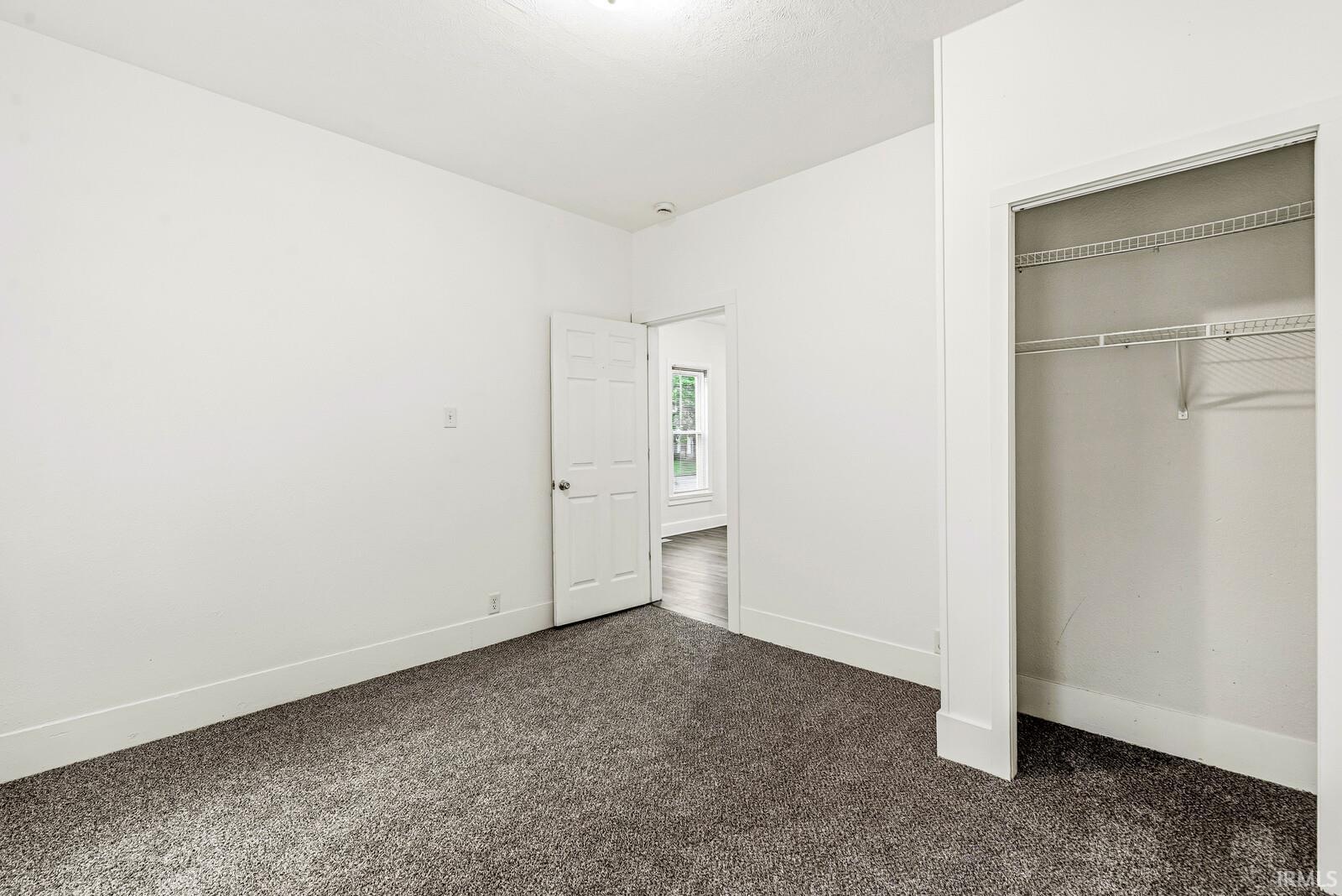 Carpeted interior room with white walls, white baseboards, and a white ceiling