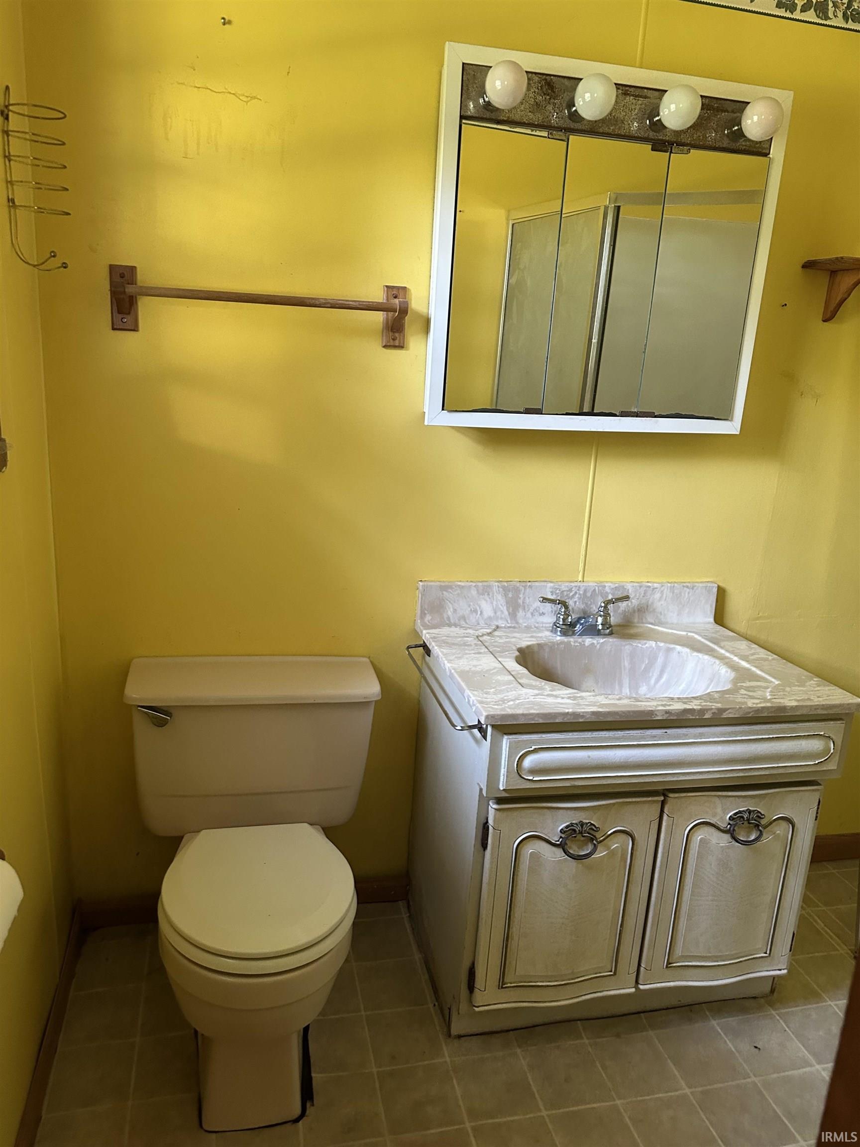 Bathroom featuring a vanity with a faux marble countertop, ceramic sink, and two-door cabinet