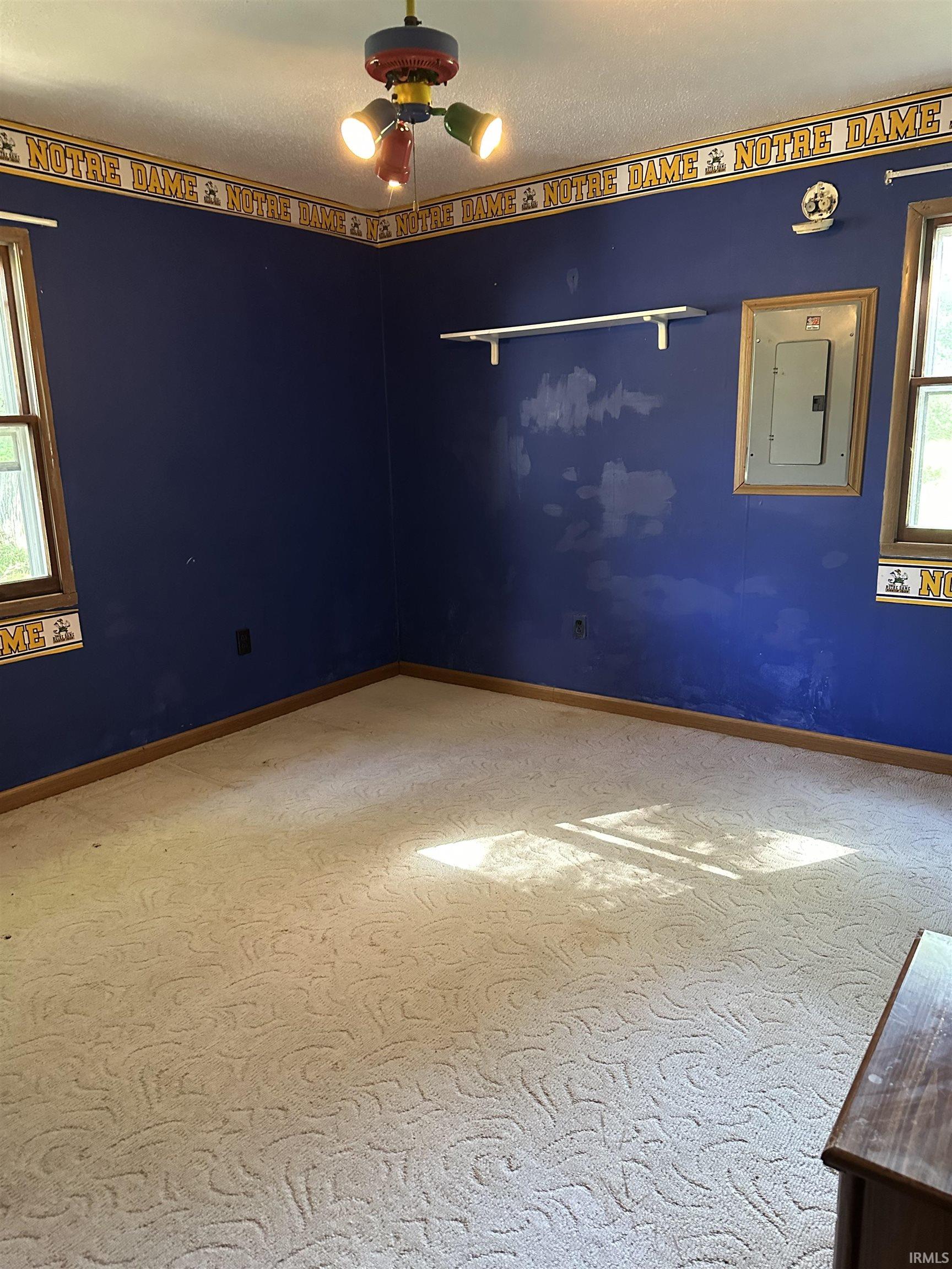 Room with patterned carpeting, blue walls, and wood trim