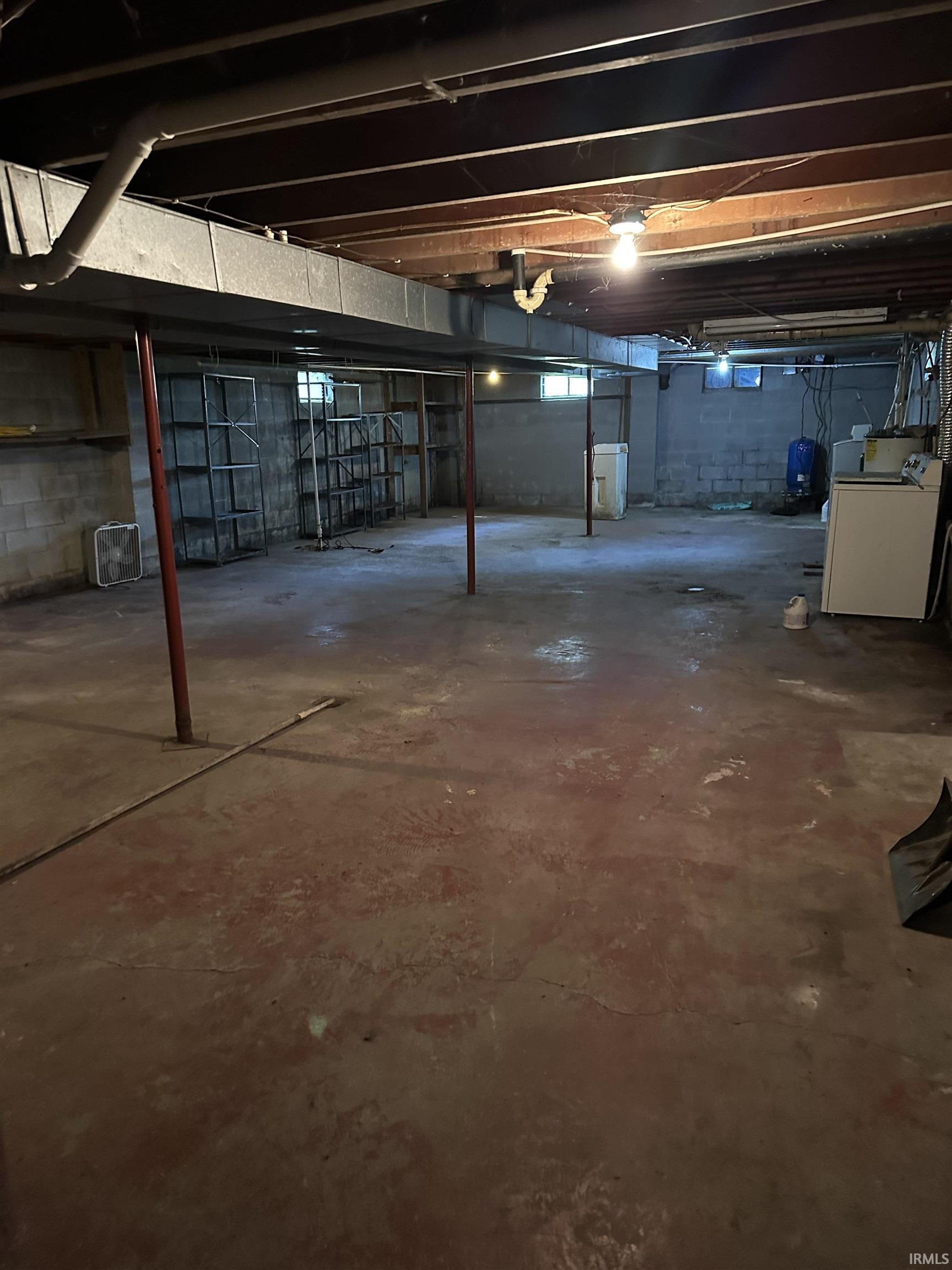 Unfinished basement with exposed ceiling joists, concrete block walls, and a concrete floor