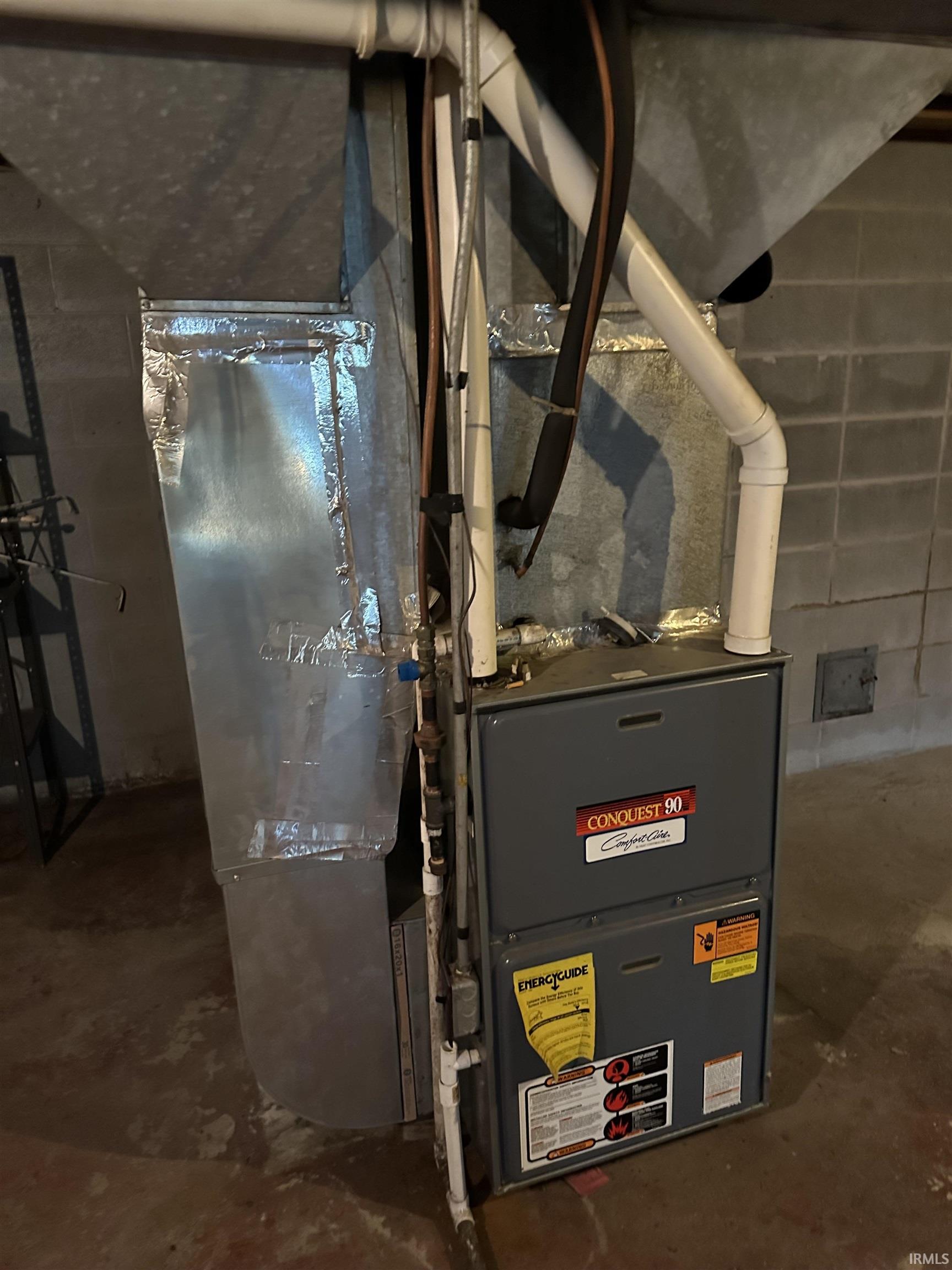HVAC system with metal ductwork, PVC piping, and concrete block walls