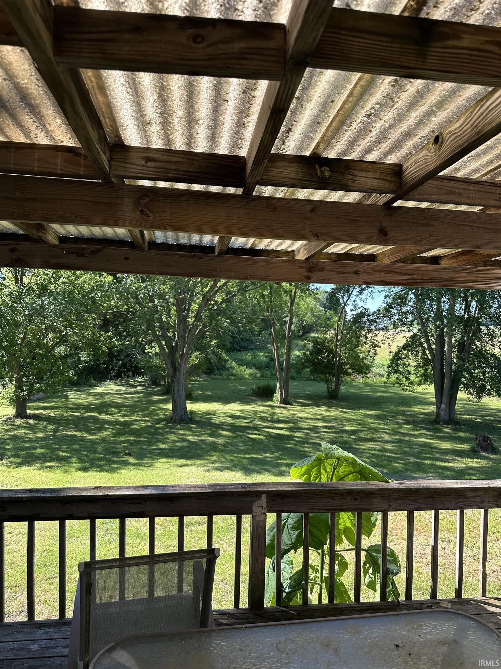Outdoor deck space featuring a wood railing and a corrugated translucent roof