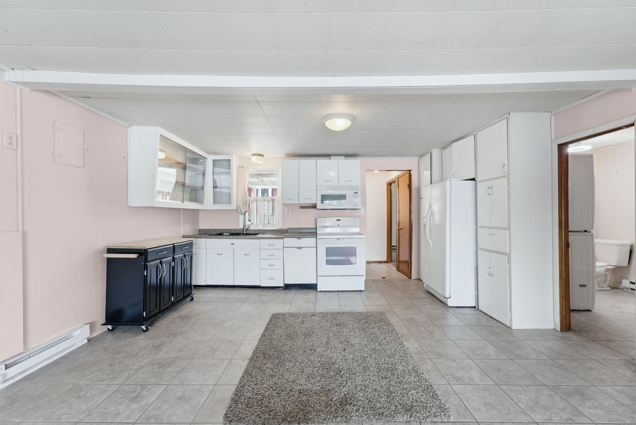 Kitchen featuring white cabinetry, grey tile flooring, white appliances, and a built-in microwave