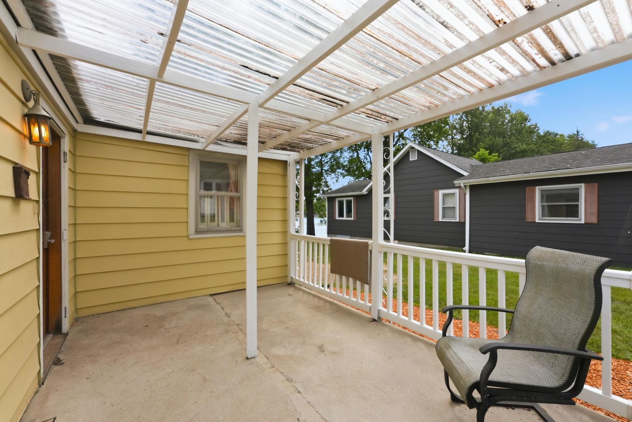 Covered concrete patio featuring a translucent panel roof and white railing