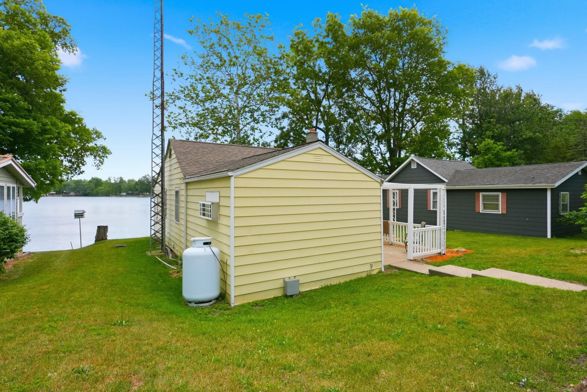 Yellow siding structure with a gable roof and visible window AC unit