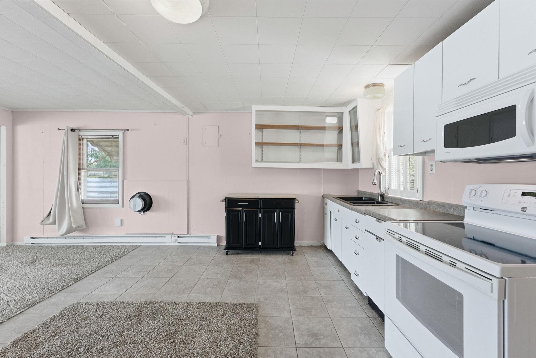 Open-concept kitchen and living area featuring white cabinetry, a built-in microwave, and a black double-basin sink