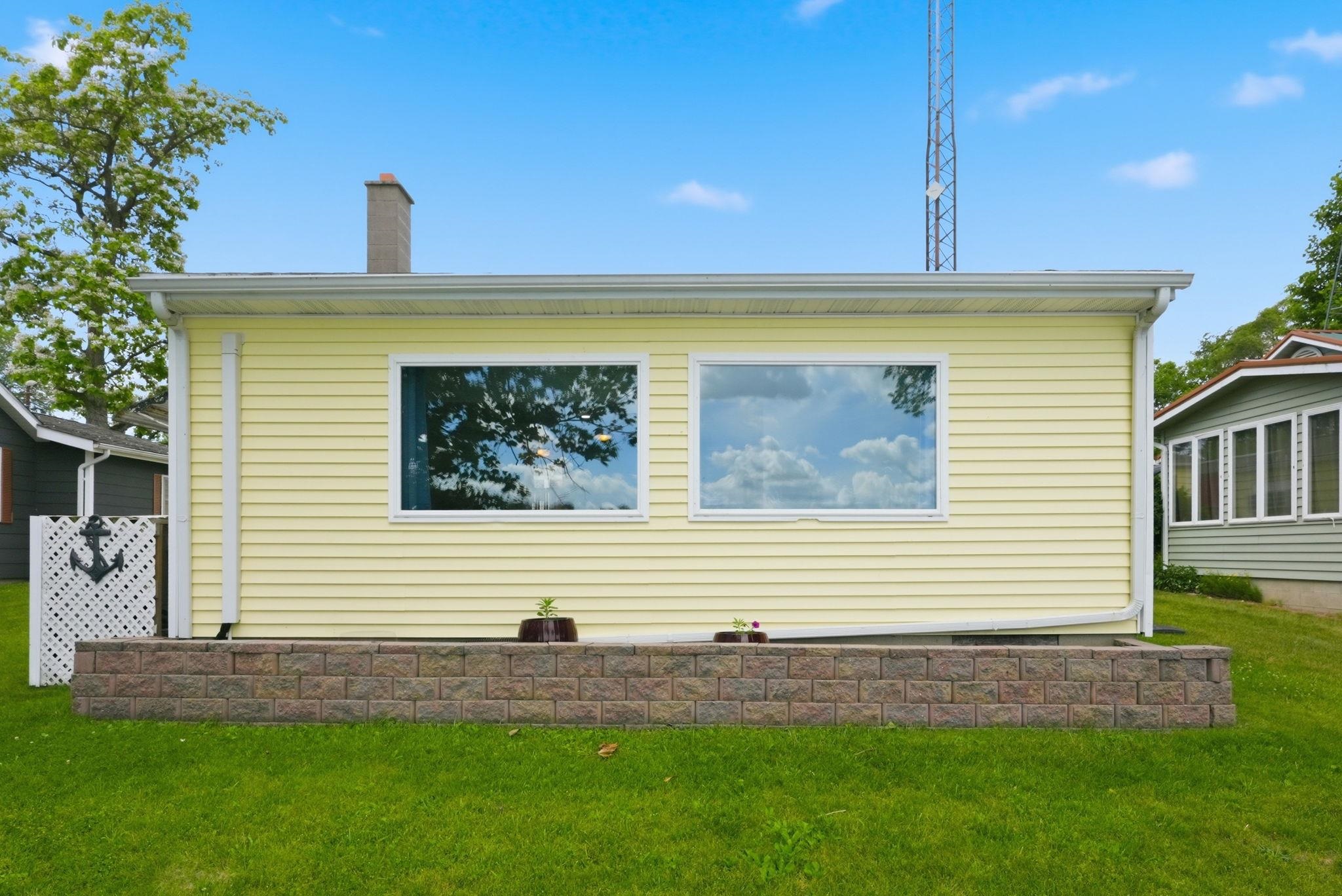 Light yellow horizontal siding exterior with two large windows and white trim