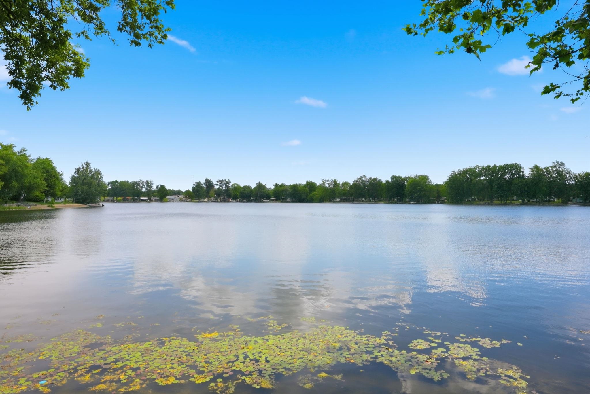 Expansive body of water featuring a calm surface and verdant shoreline