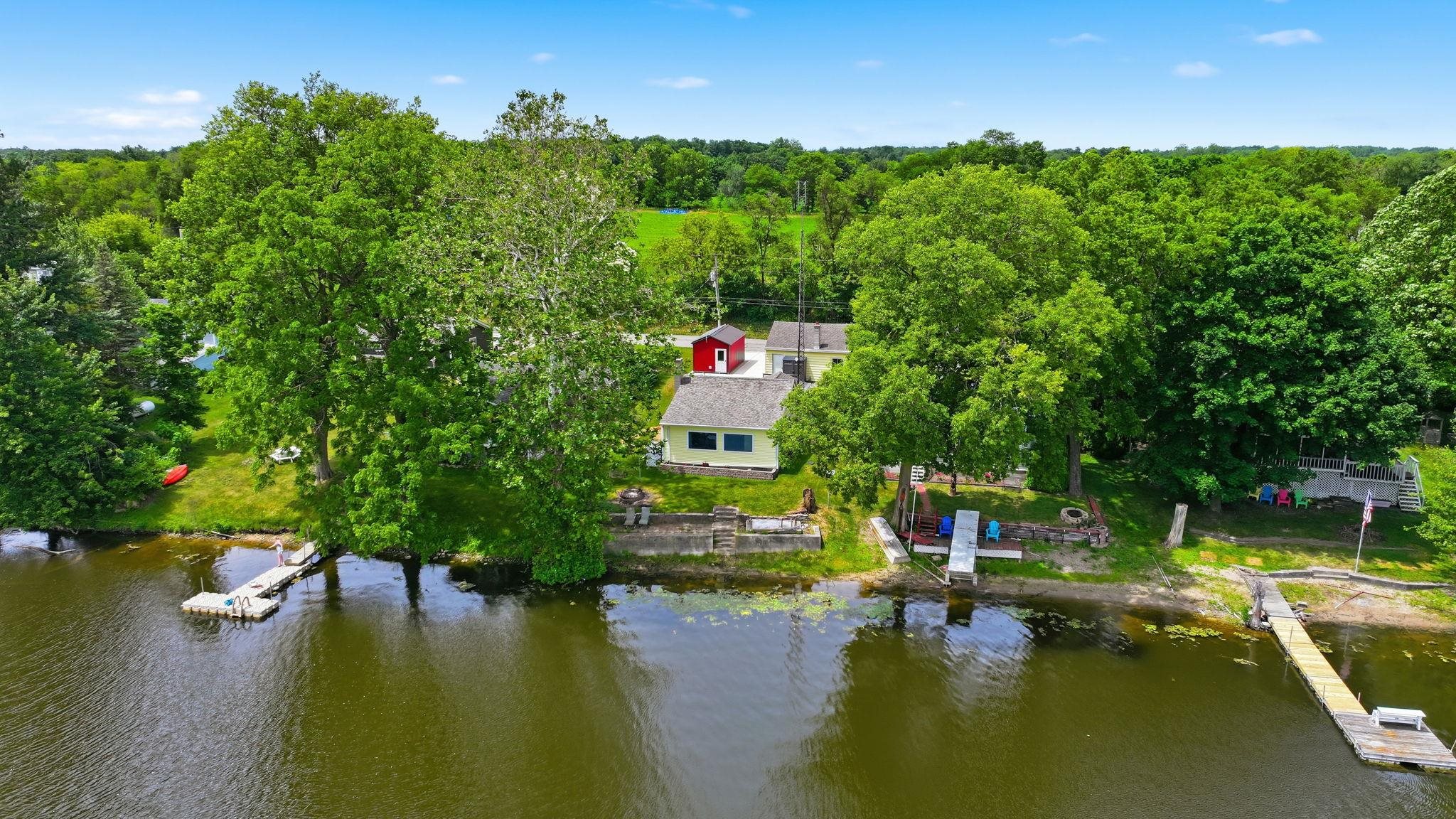 Waterfront property featuring a dock, ample tree coverage, and an elevated patio area