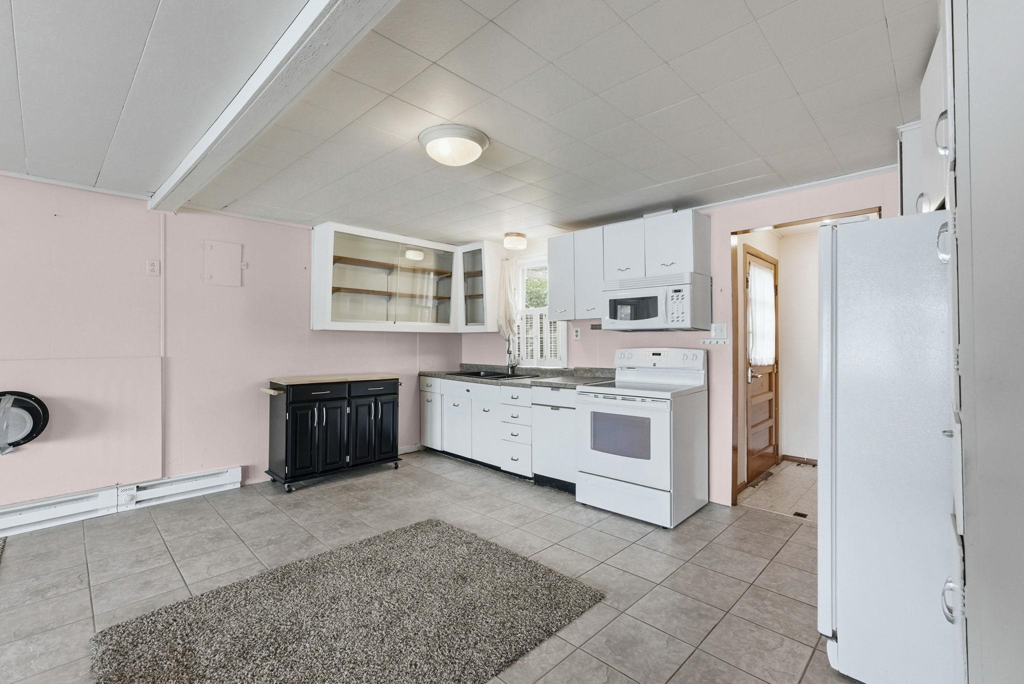 Kitchen featuring tile flooring, white cabinetry, integrated microwave, and a white electric range