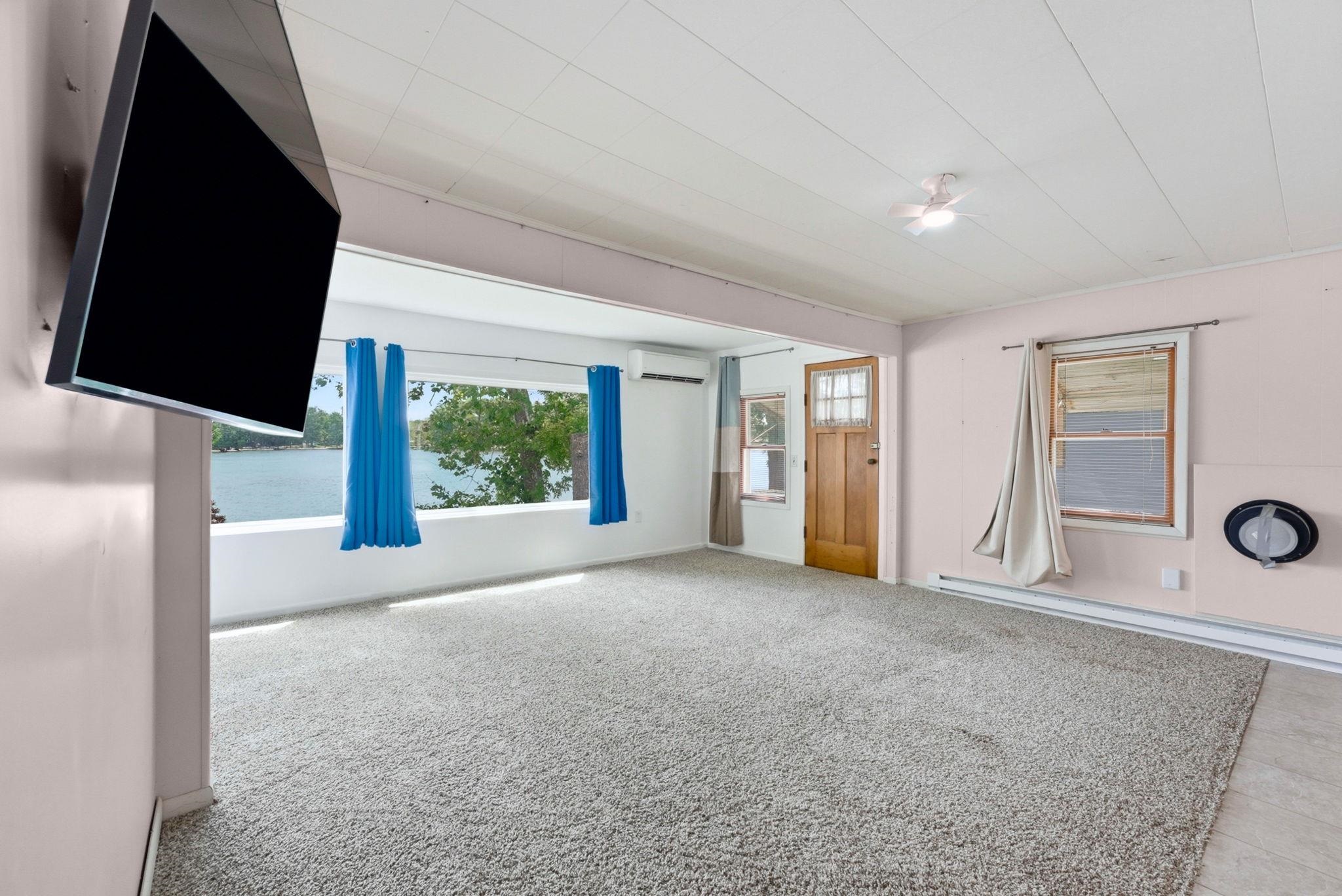 Spacious room featuring broadloom carpeting and a large window overlooking a body of water