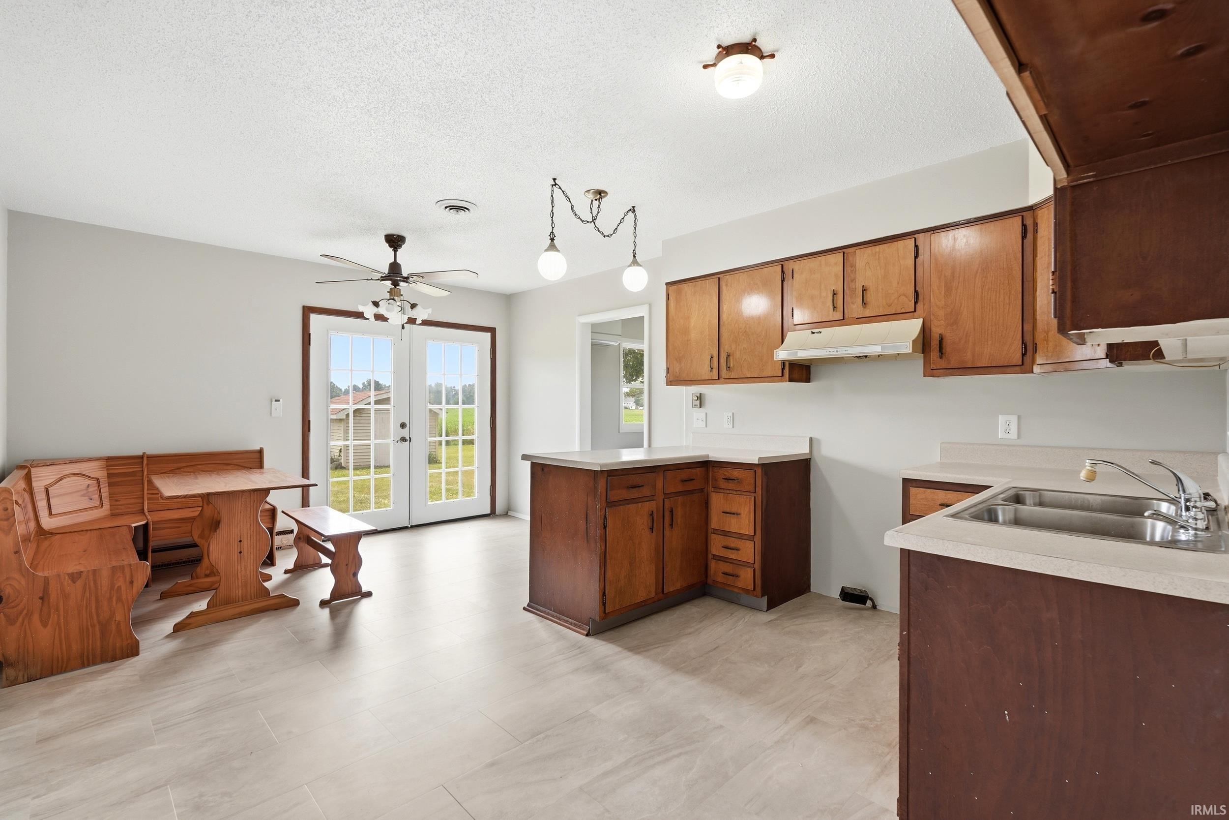 Kitchen featuring wood cabinetry, white countertops, stainless steel double basin sink, and tile flooring