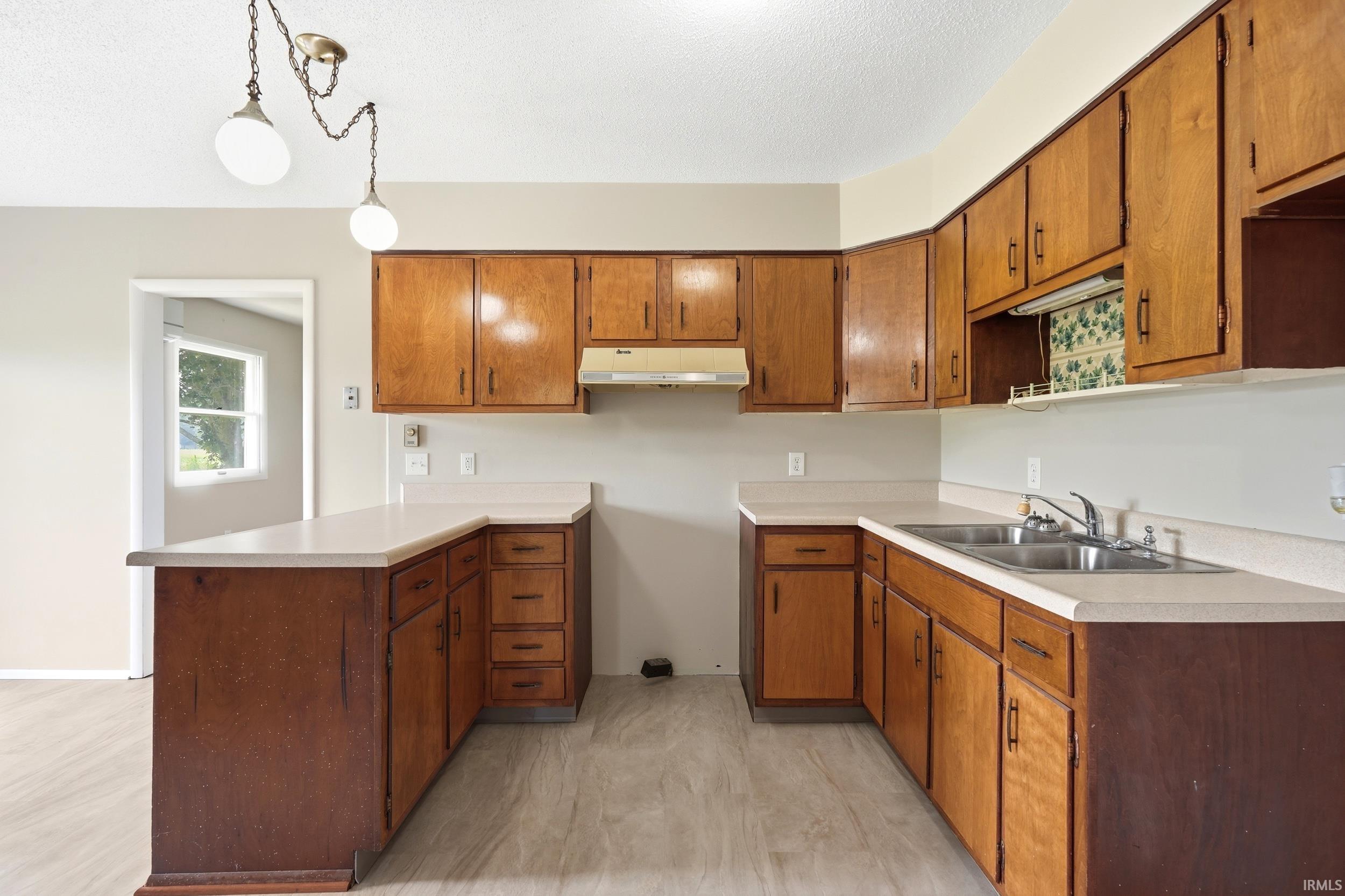 Kitchen with wood-finish cabinetry, solid surface countertops, and a double basin sink