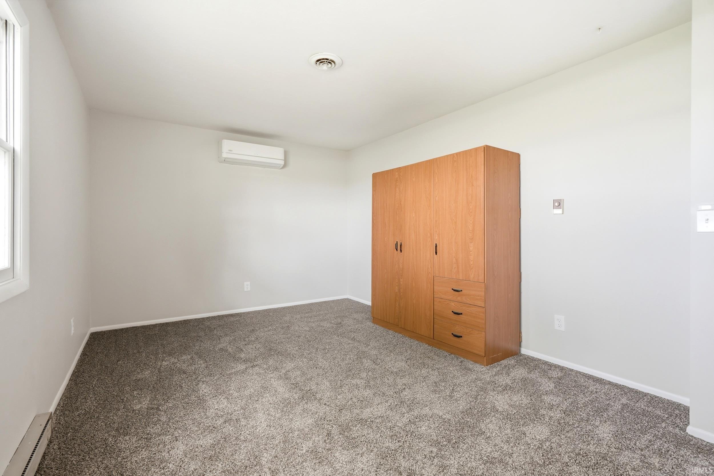 Spacious room featuring neutral carpeting, light gray wall paint, and white trim