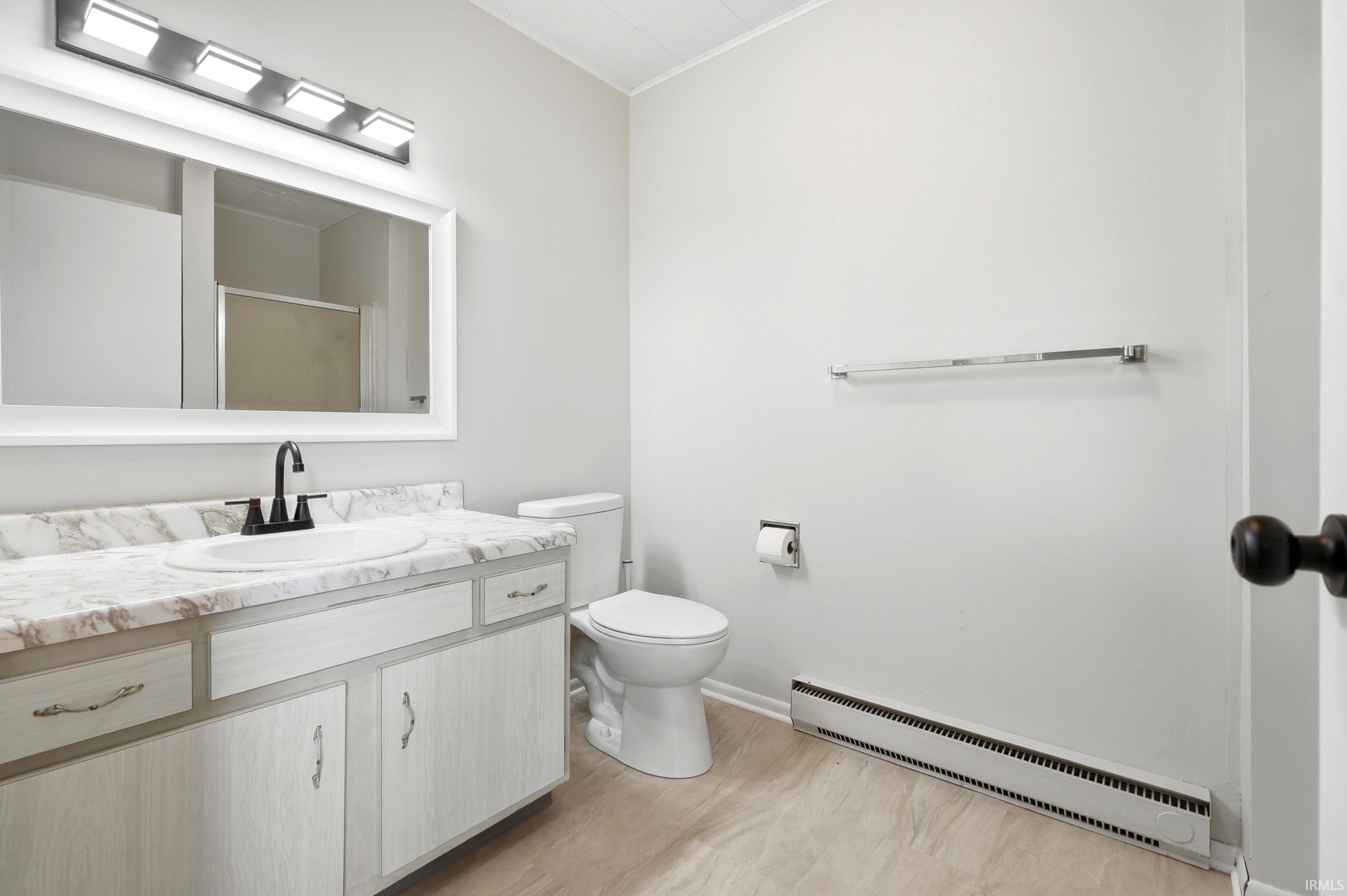 Bathroom featuring a vanity with a faux marble countertop, white cabinetry with silver hardware, and a framed mirror