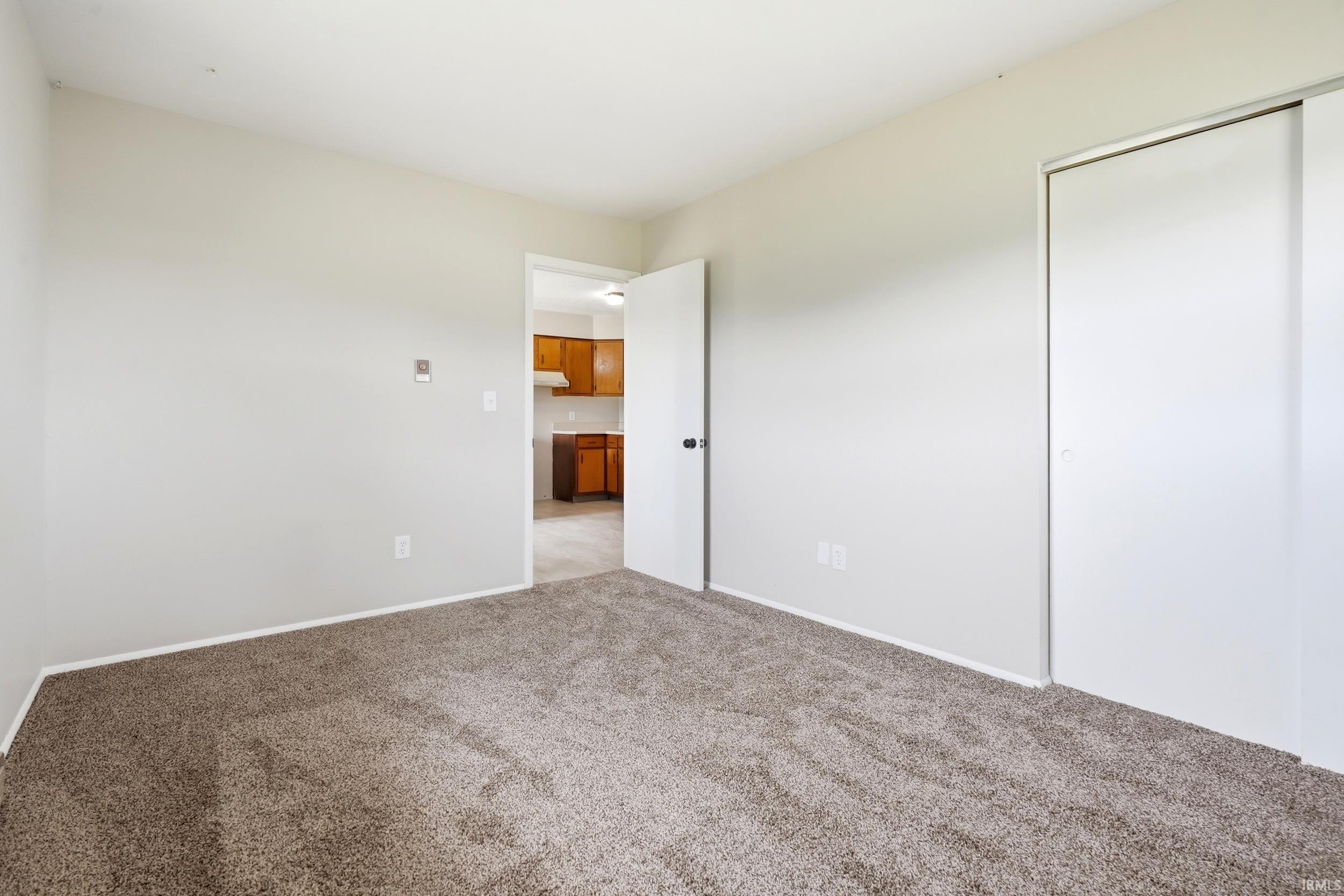 Carpeted room featuring light neutral wall paint and a sliding closet door