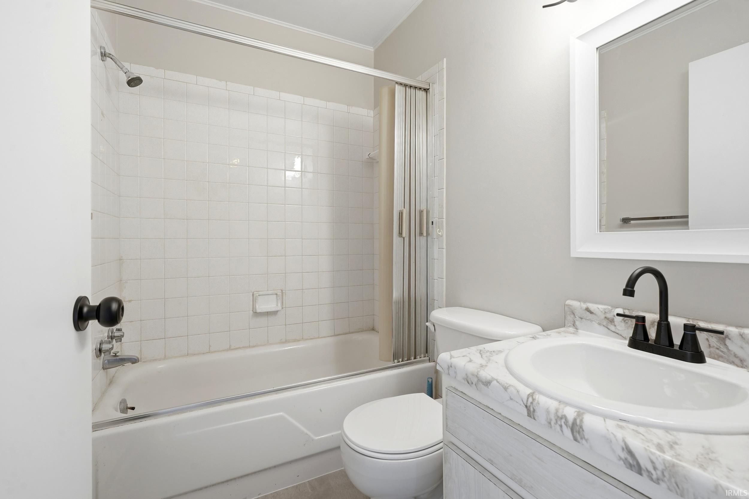 Bathroom with white tile shower surround, shower/tub combination, and a single vanity with a white basin and matte black faucet