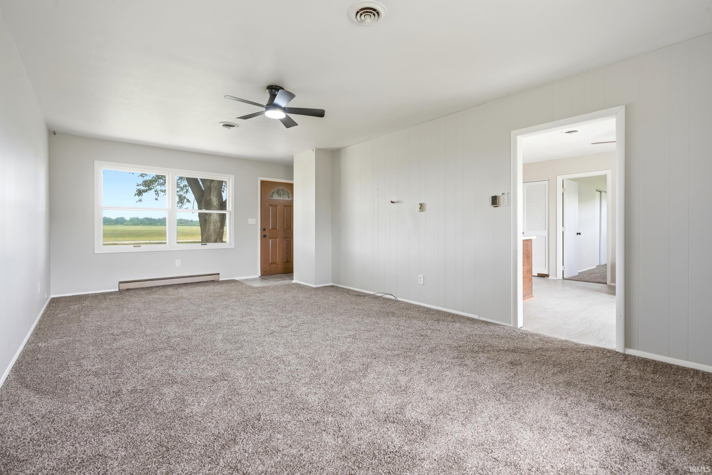 Spacious room featuring gray wall paint and textured carpet flooring