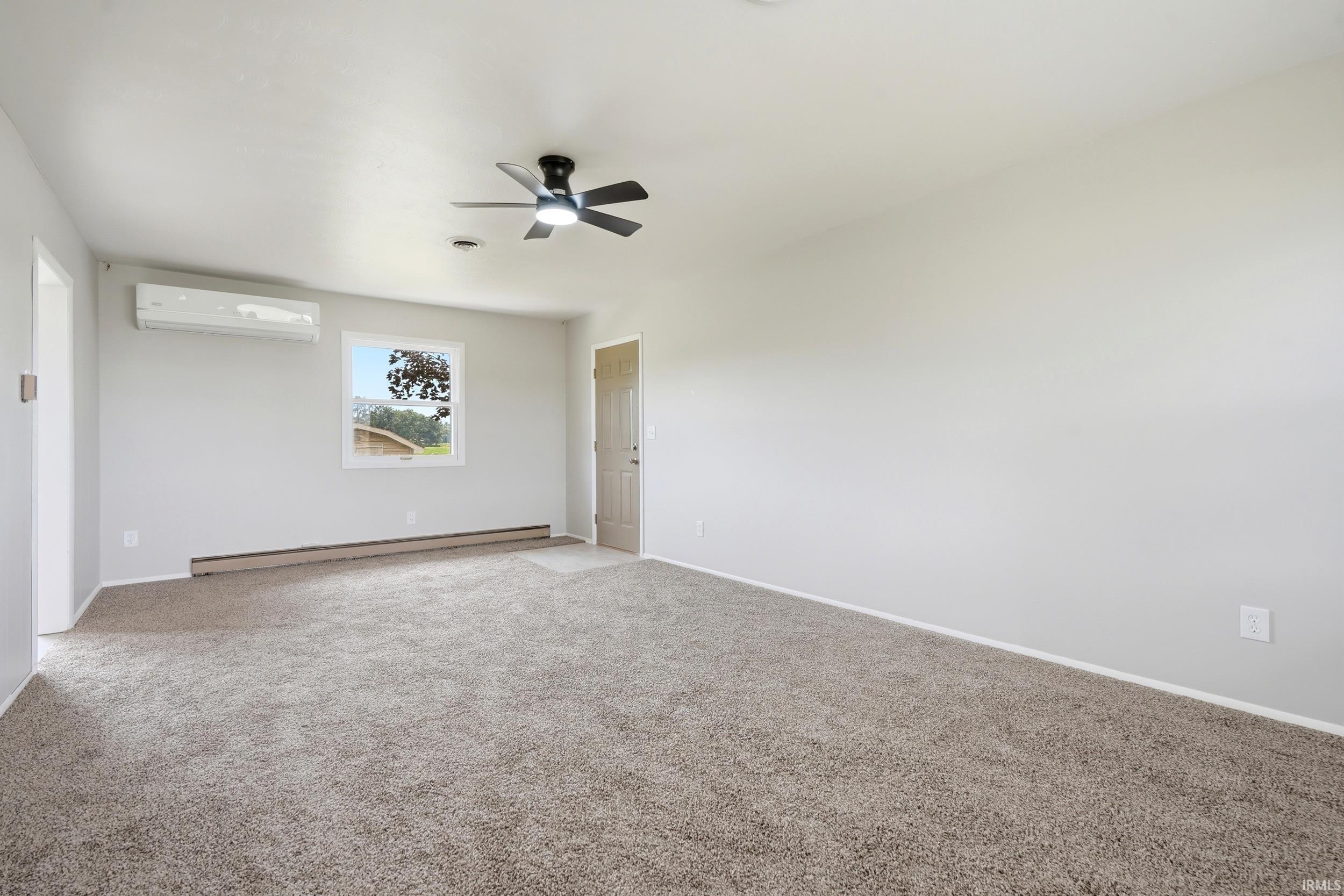Spacious room featuring neutral carpeting, light gray wall paint, and a ceiling fan with integrated lighting