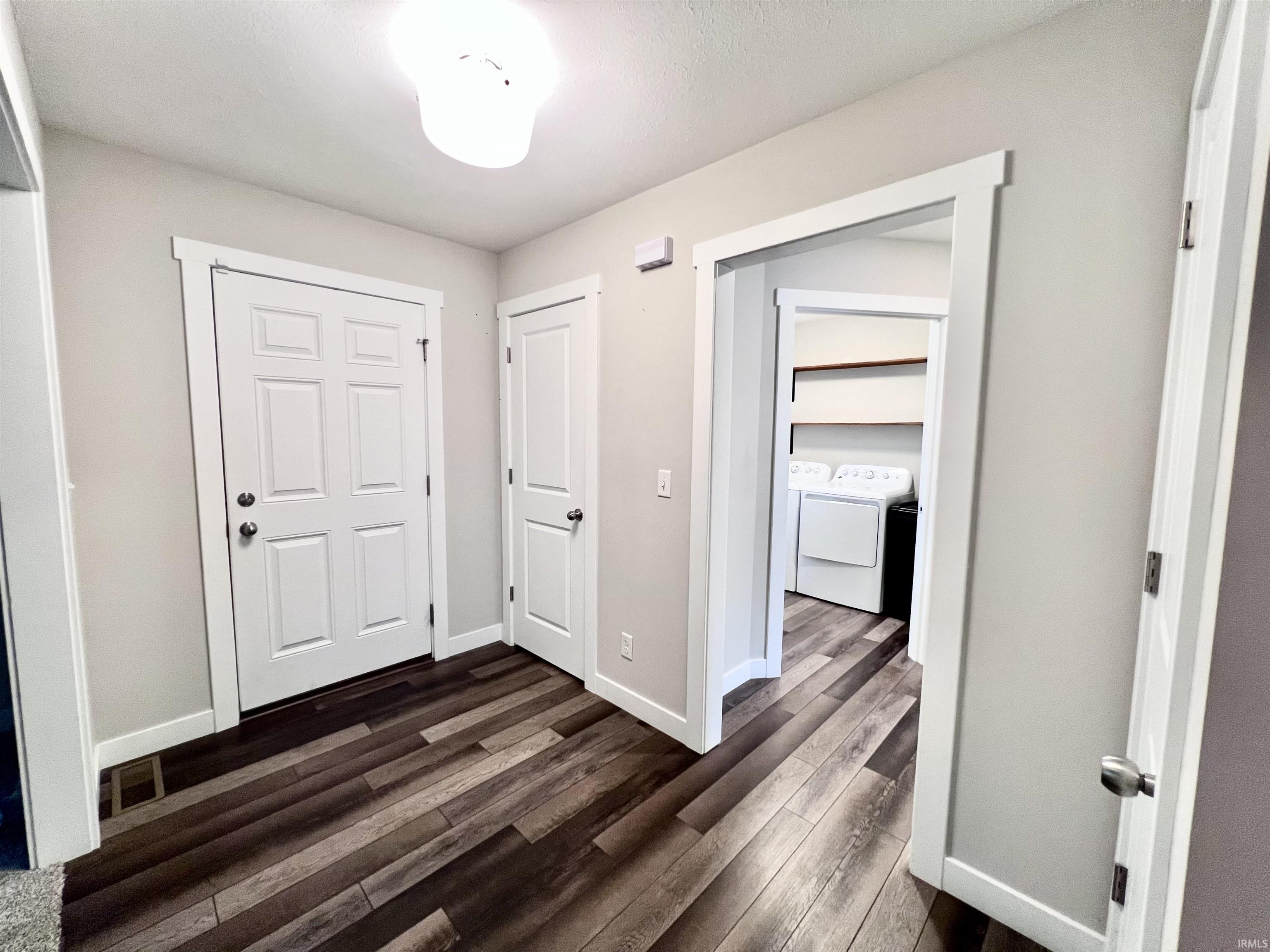 Wood-finish flooring, white paneled doors, ceiling-mounted light fixture, and light-toned wall paint