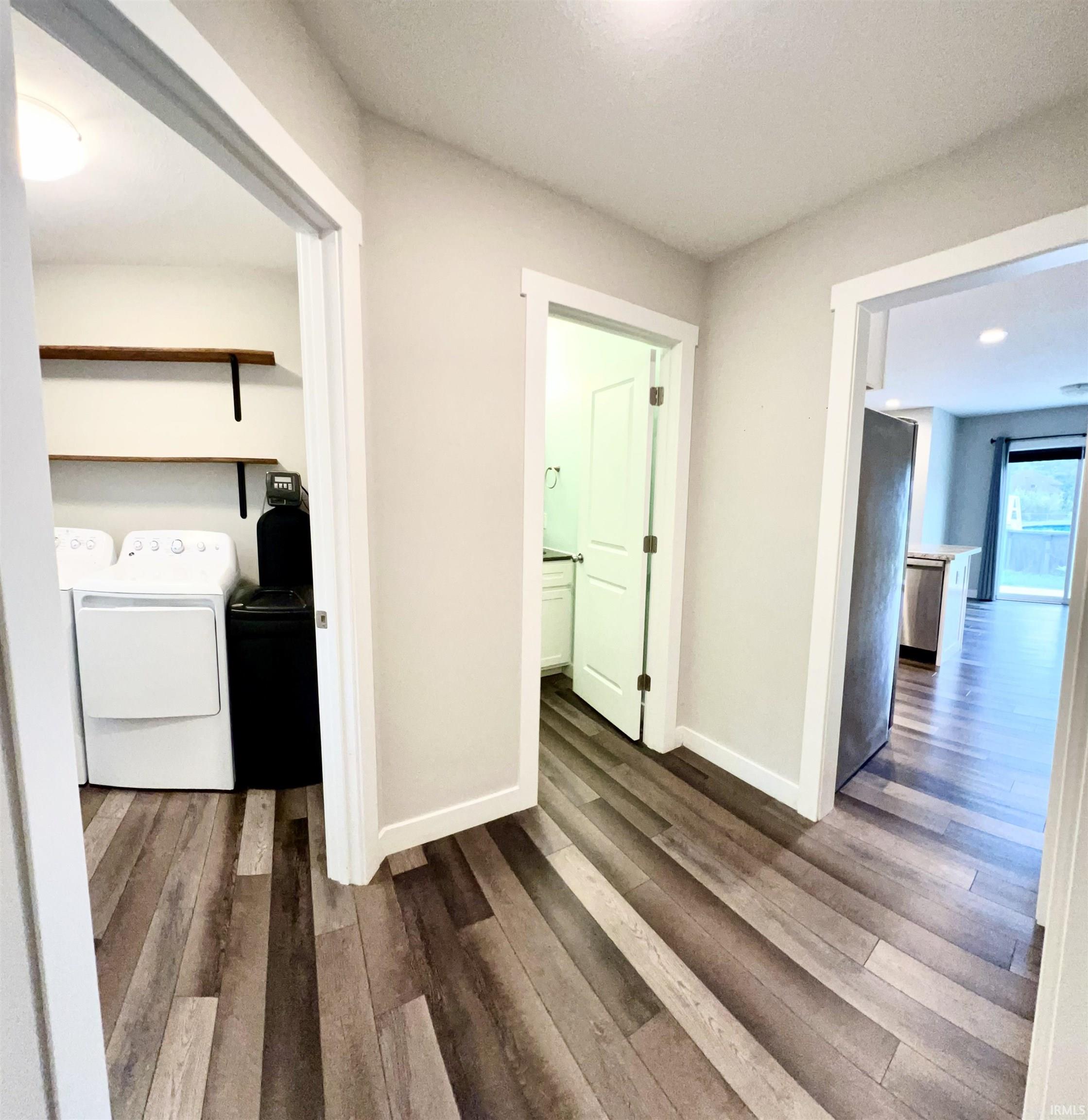 Wood-finish flooring throughout, bright white trim, laundry area with open shelving, and a well-lit powder room