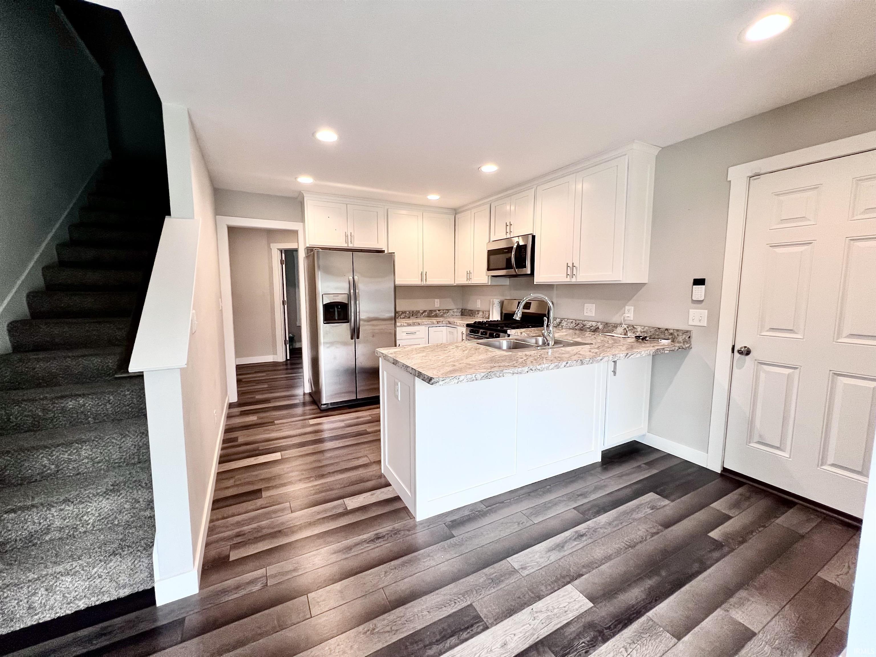 Modern kitchen featuring white cabinetry, stainless steel appliances, and granite countertops with a large island