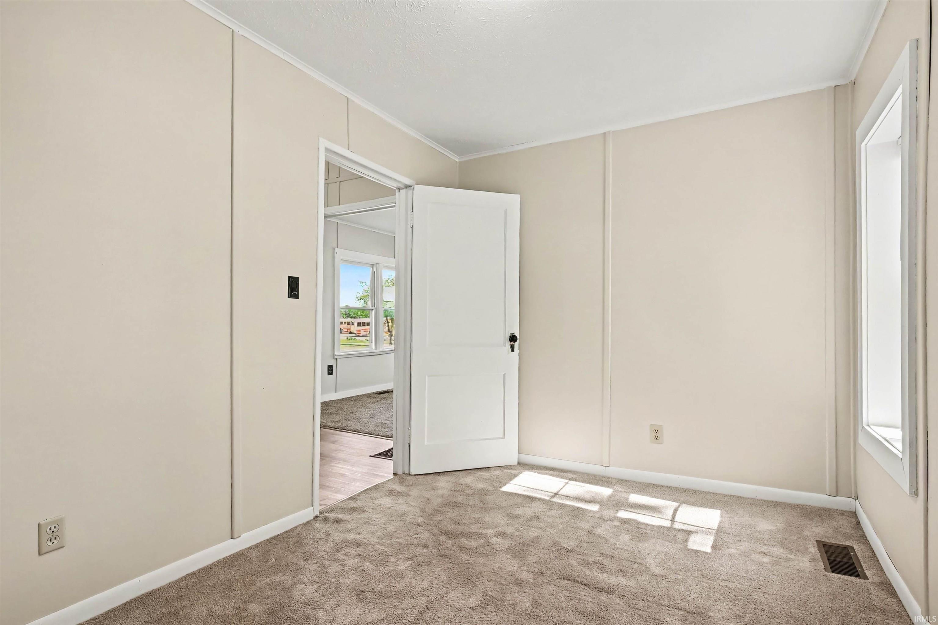 Carpeted room featuring light-toned vertical paneling and white trim
