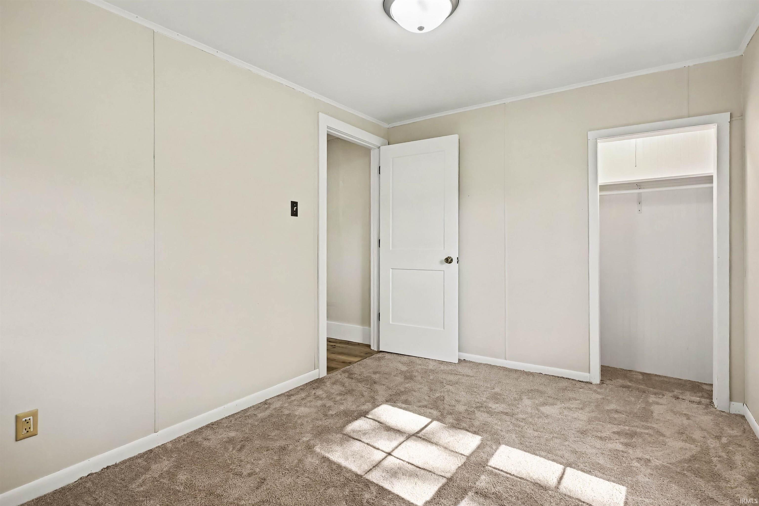 Neutral-toned room featuring light beige walls and a matching textured carpet