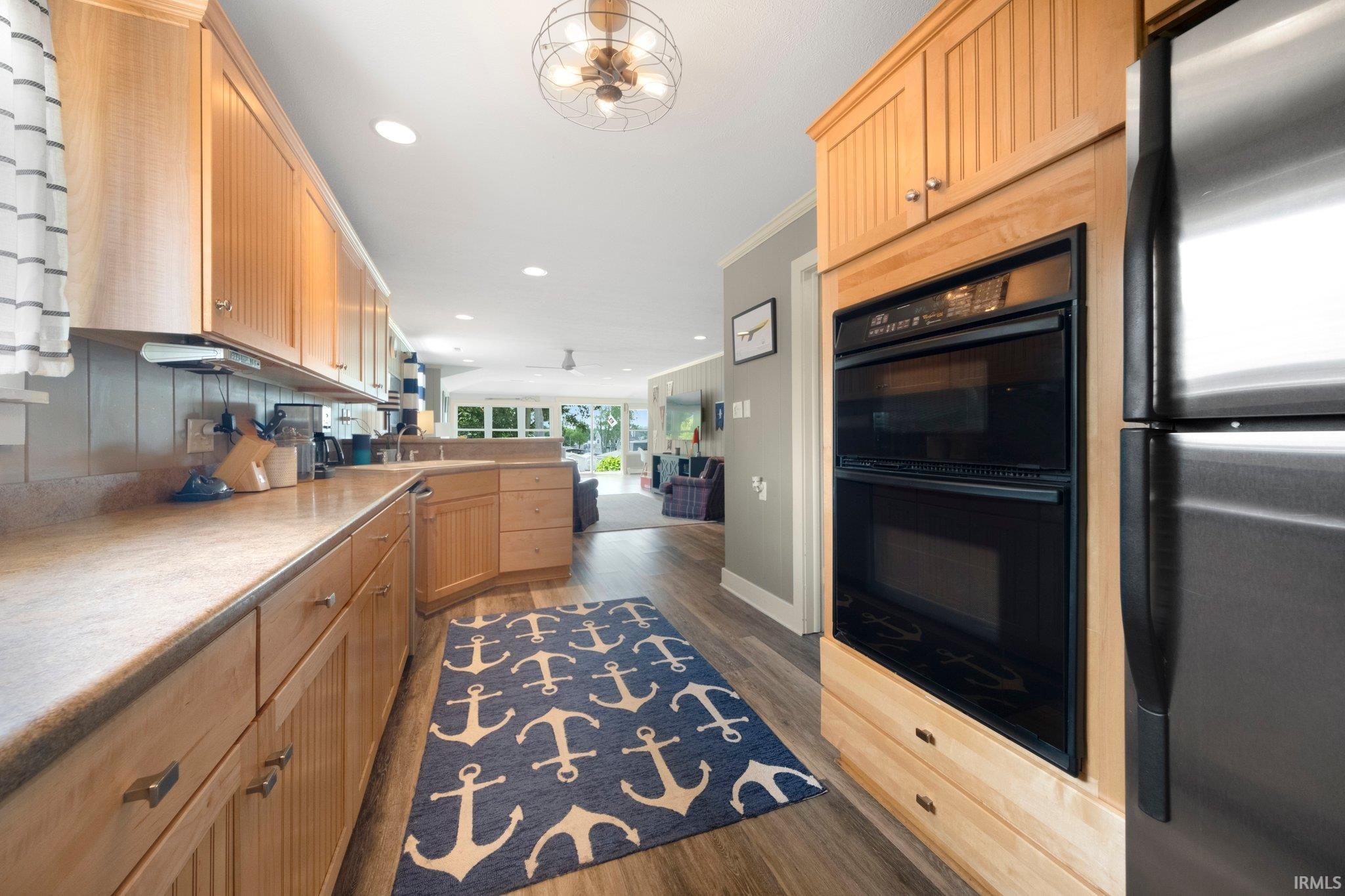 Kitchen featuring light wood cabinetry, light countertops, wood-finish flooring, and a stainless steel refrigerator