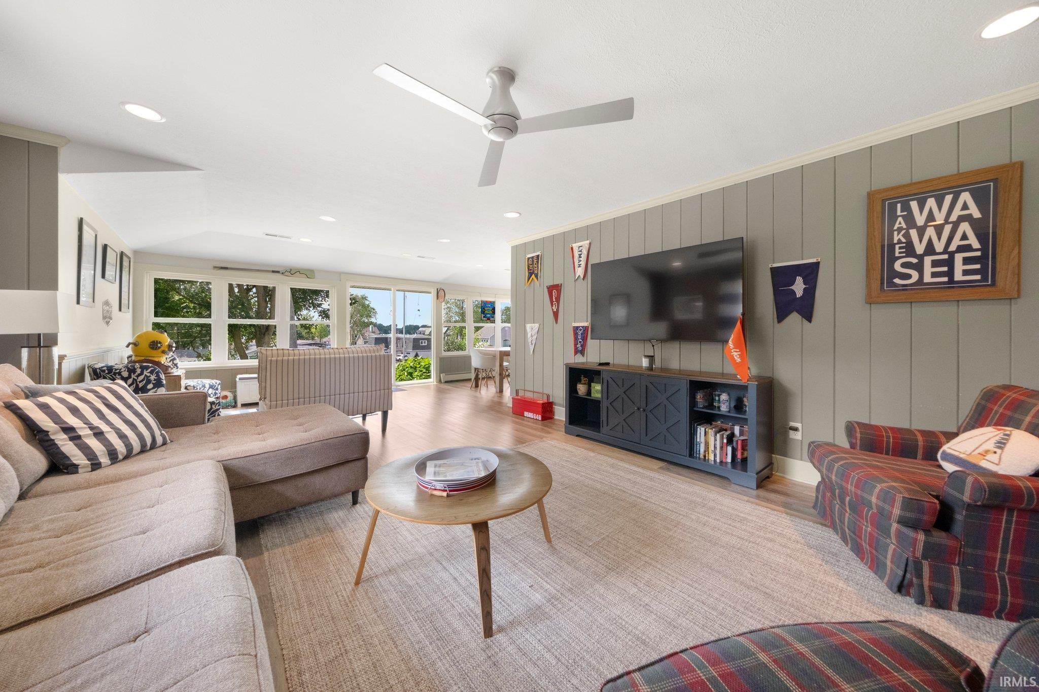 Spacious living area featuring plank wall paneling, recessed lighting, and a modern ceiling fan