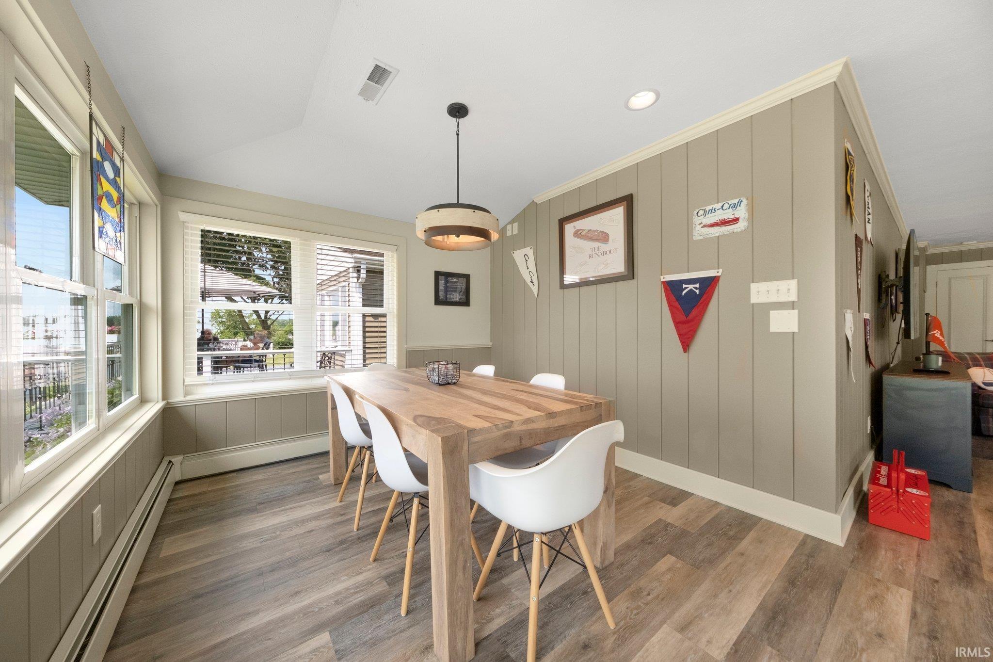 Dining area featuring a contemporary wooden table, wood-finish flooring, recessed lighting, and a modern pendant light fixture