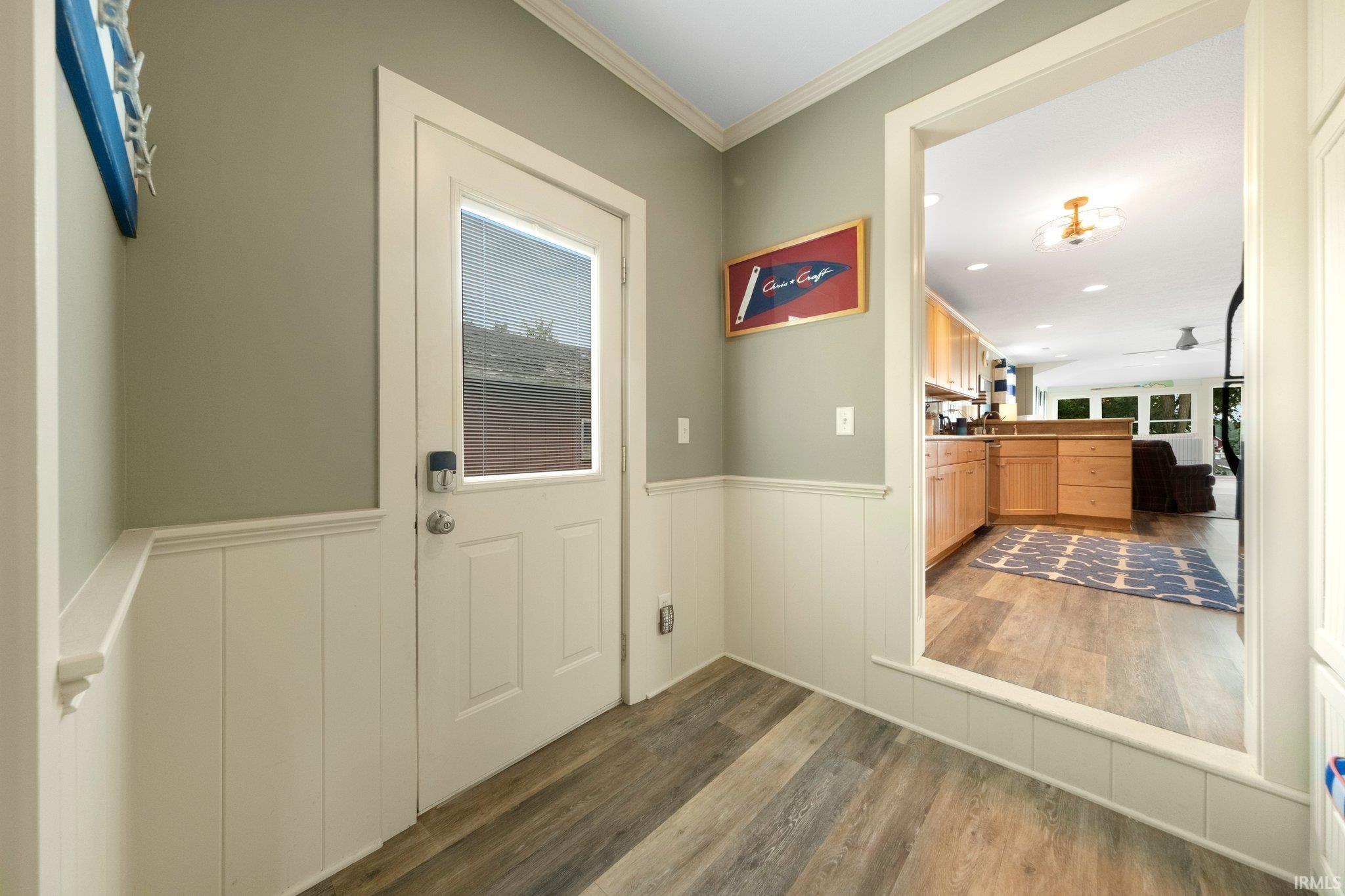 Entryway with wood-finish flooring, white wainscoting, and a full-light panel door