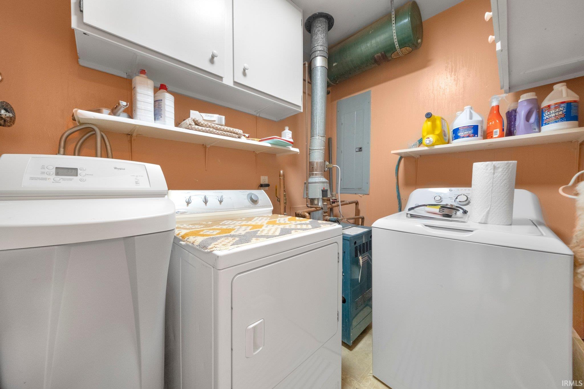 Dedicated utility area featuring a water softener, dryer, washing machine, and upper cabinetry for storage