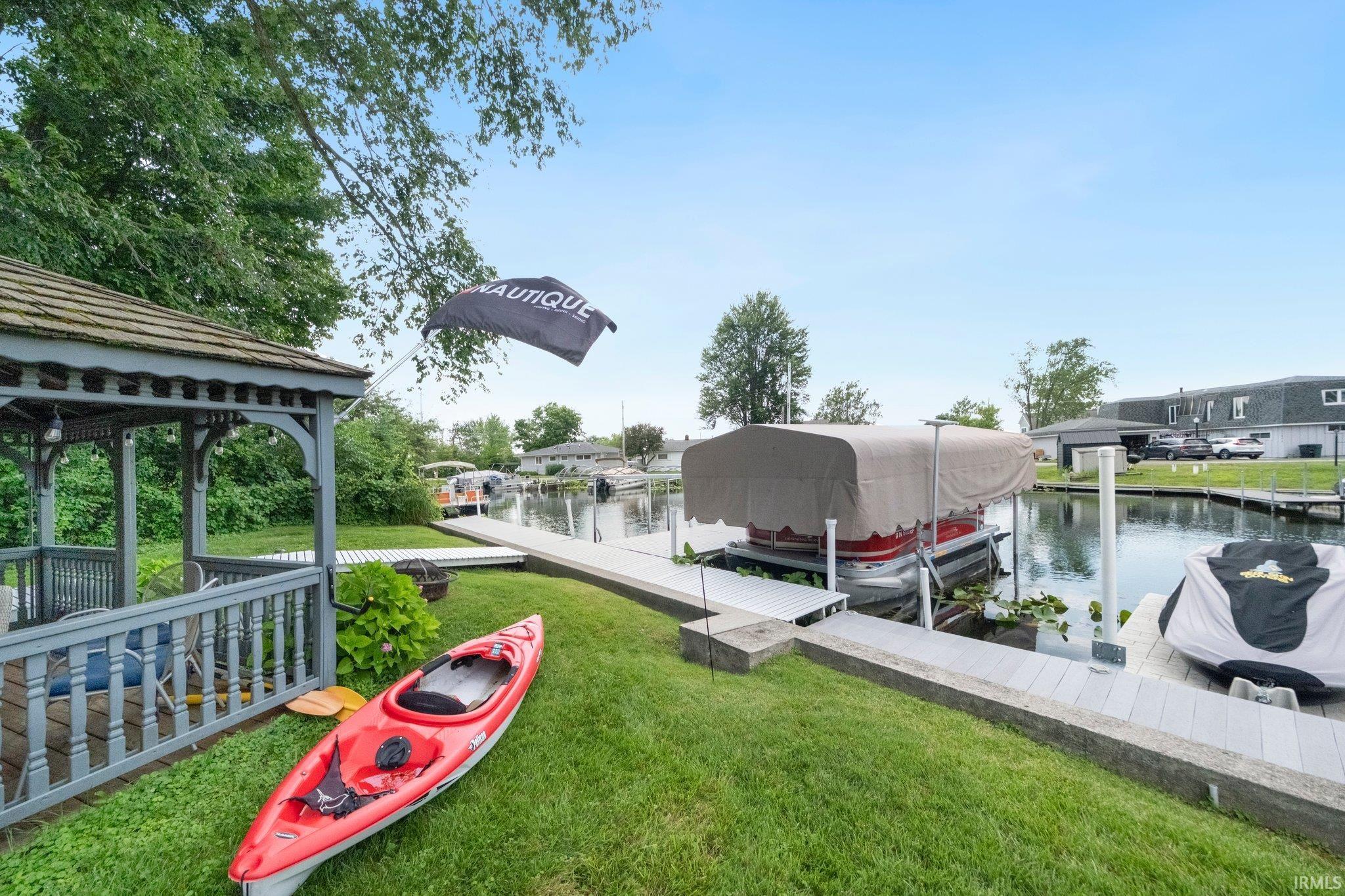 Waterside property featuring a built-in boat lift, private dock, and waterside gazebo with a shingled roof
